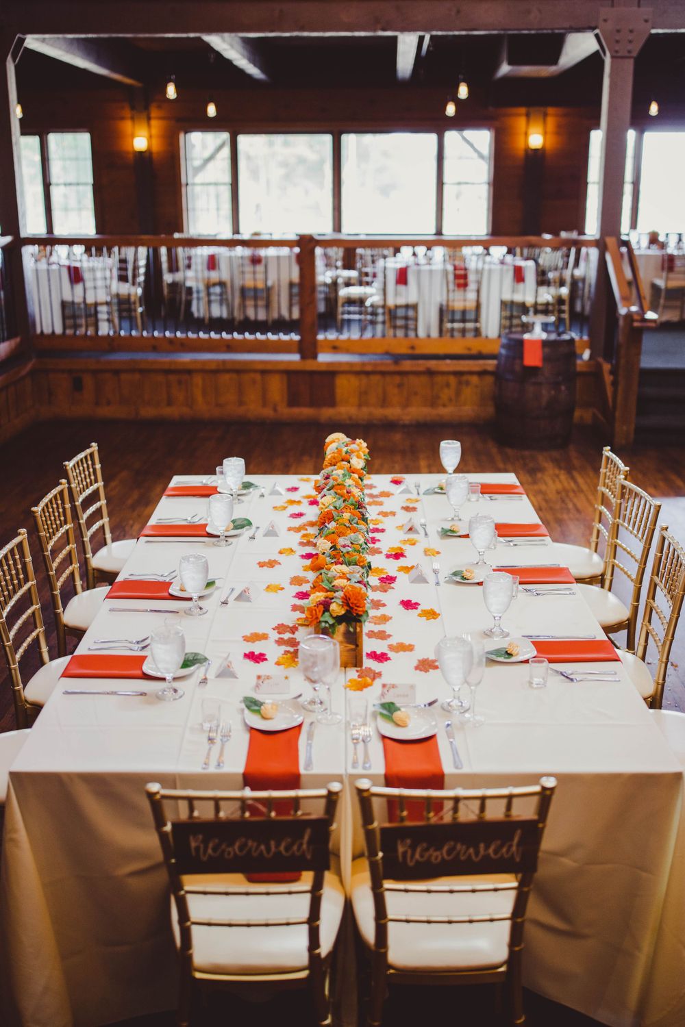Elegant wedding reception table set with orange accents and reserved signs.