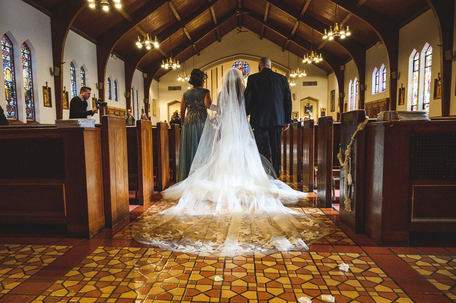 rear portrait of bride walking down isle with her parents