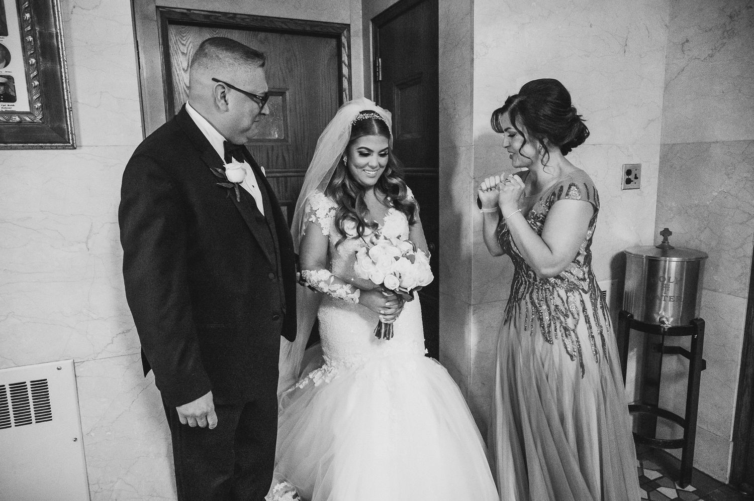 bride getting ready with mom and dad before walking down the isle