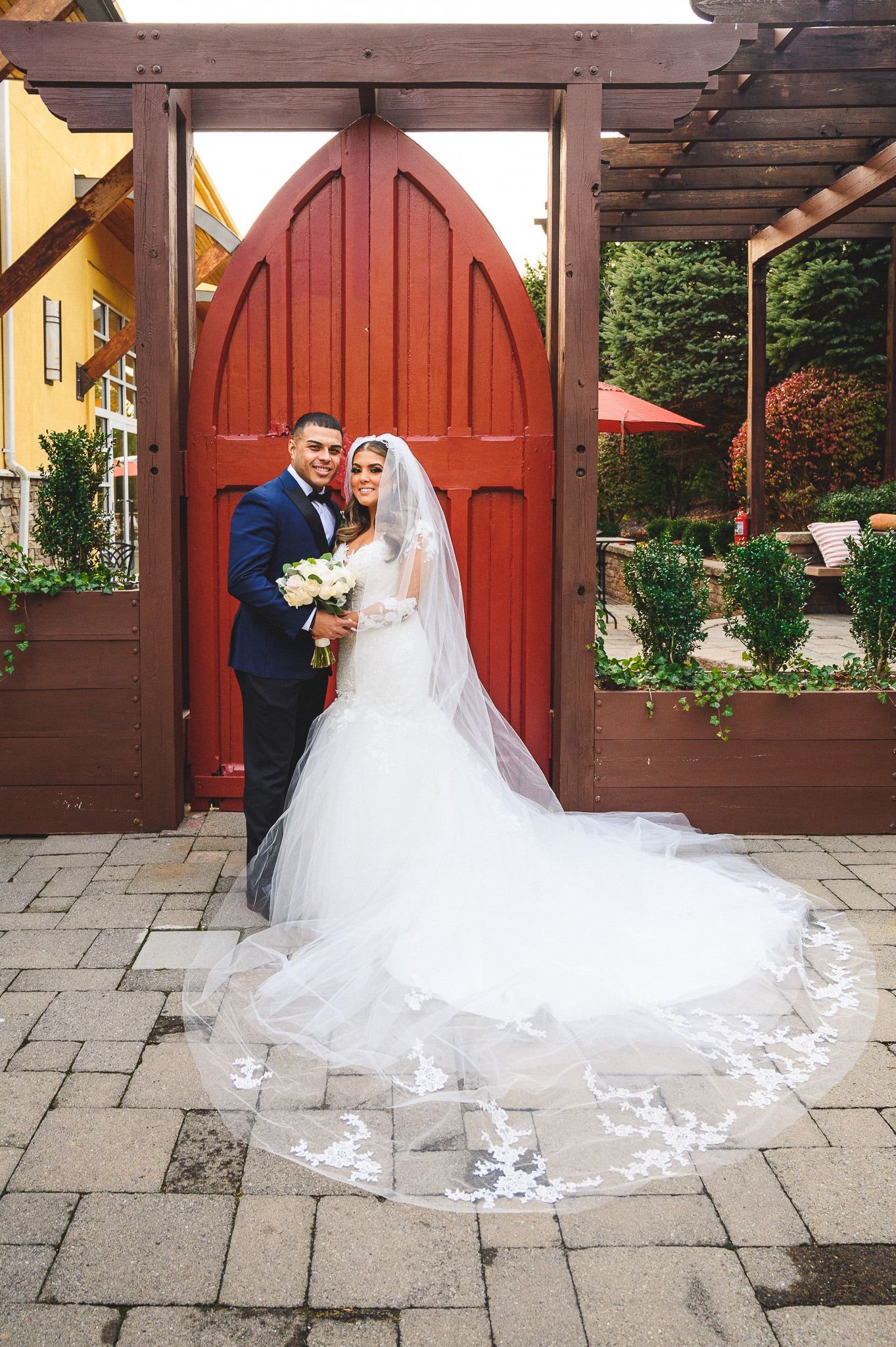 bride and groom portrait in front of red doors at stone house