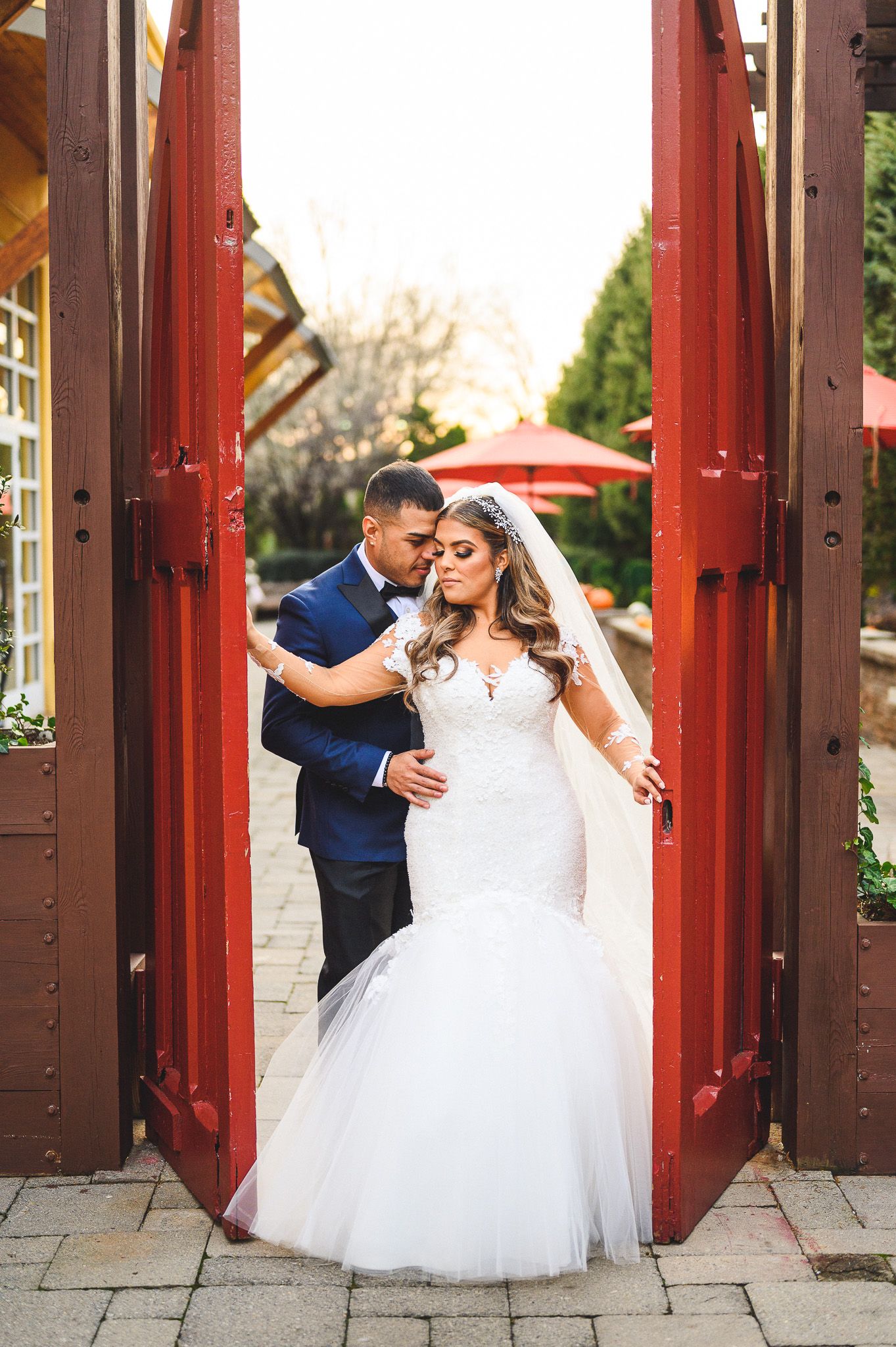 groom holding his bride in between red doors at stone house