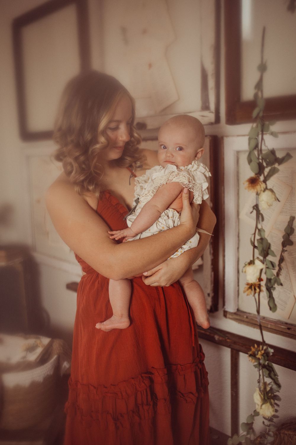 Intimate portrait in warm tones showing tender moment with baby in lace dress.