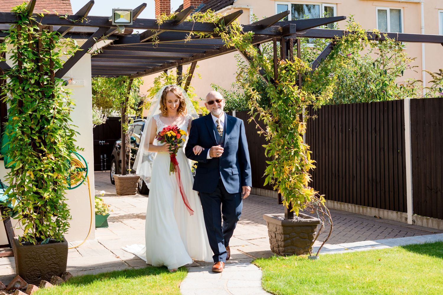 Small Garden Wedding Bride being walk down garden path by father