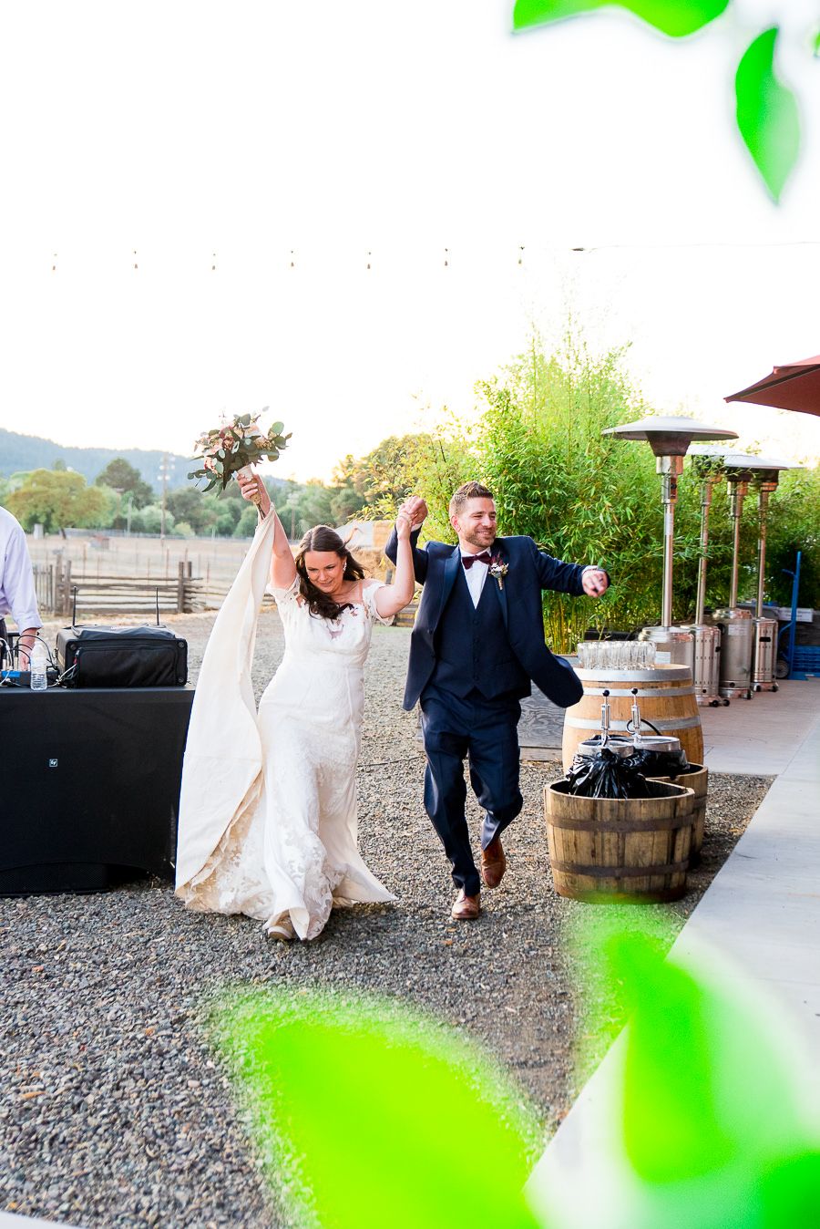 bride and groom hold hands and cheer as they walk in to wedding guests at reception on Pennyroyal farm