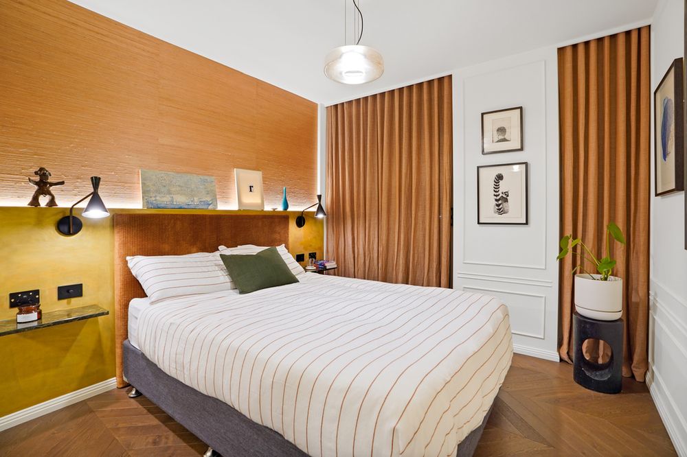Contemporary bedroom with olive accent wall, wooden panels, and striped bedding in neutral tones.
