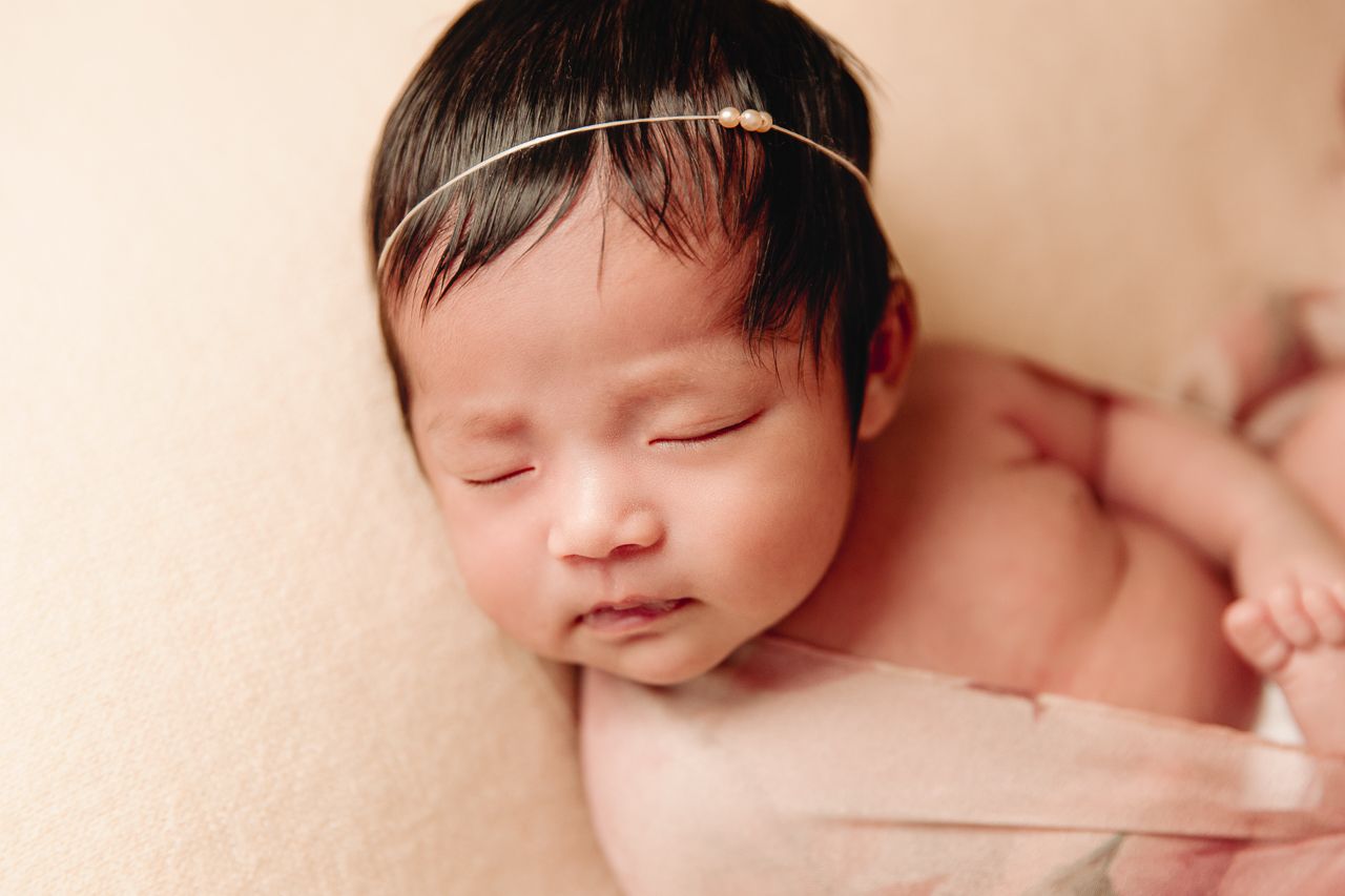 baby laying on back on peach blanket