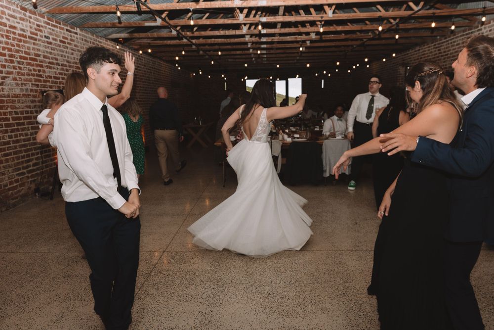 Wedding guests dancing and celebrating in rustic brick venue during reception.