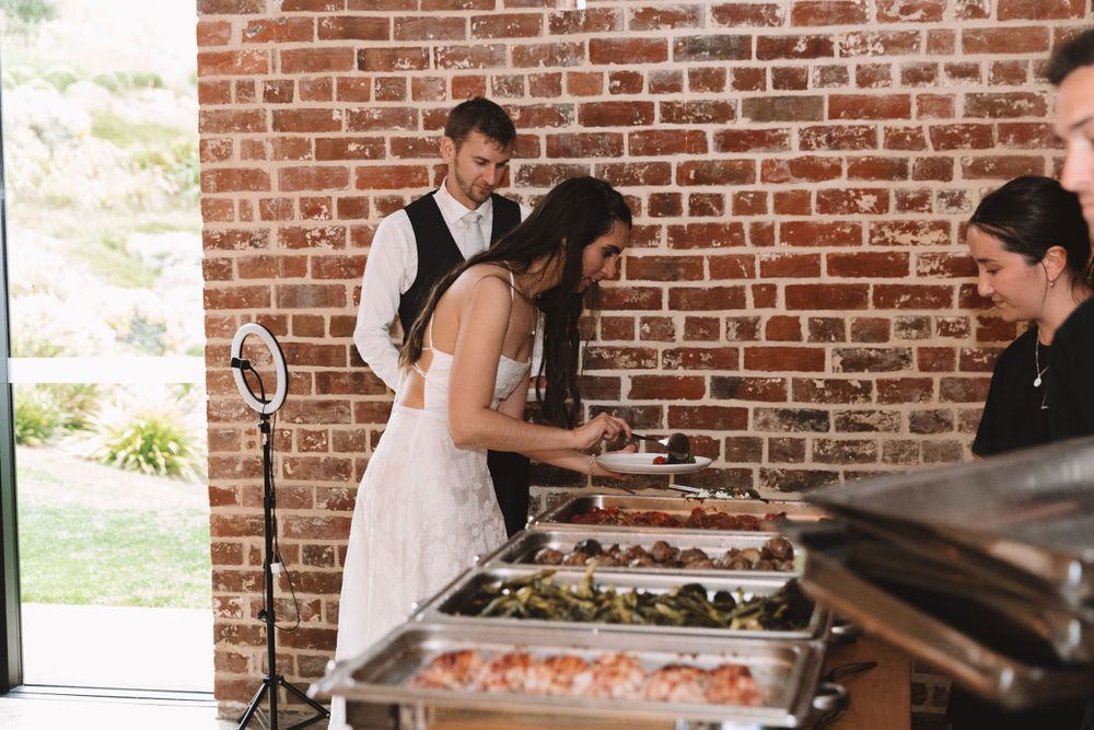Wedding buffet setup with food stations against rustic brick wall background.