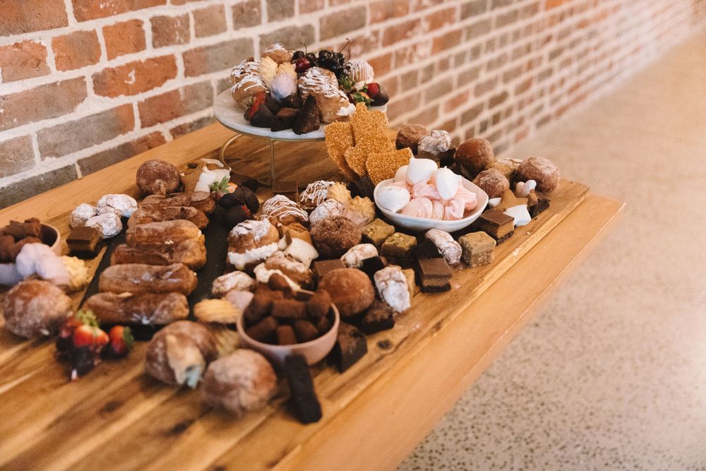 Assorted cookies and desserts arranged on wooden serving boards against brick backdrop.
