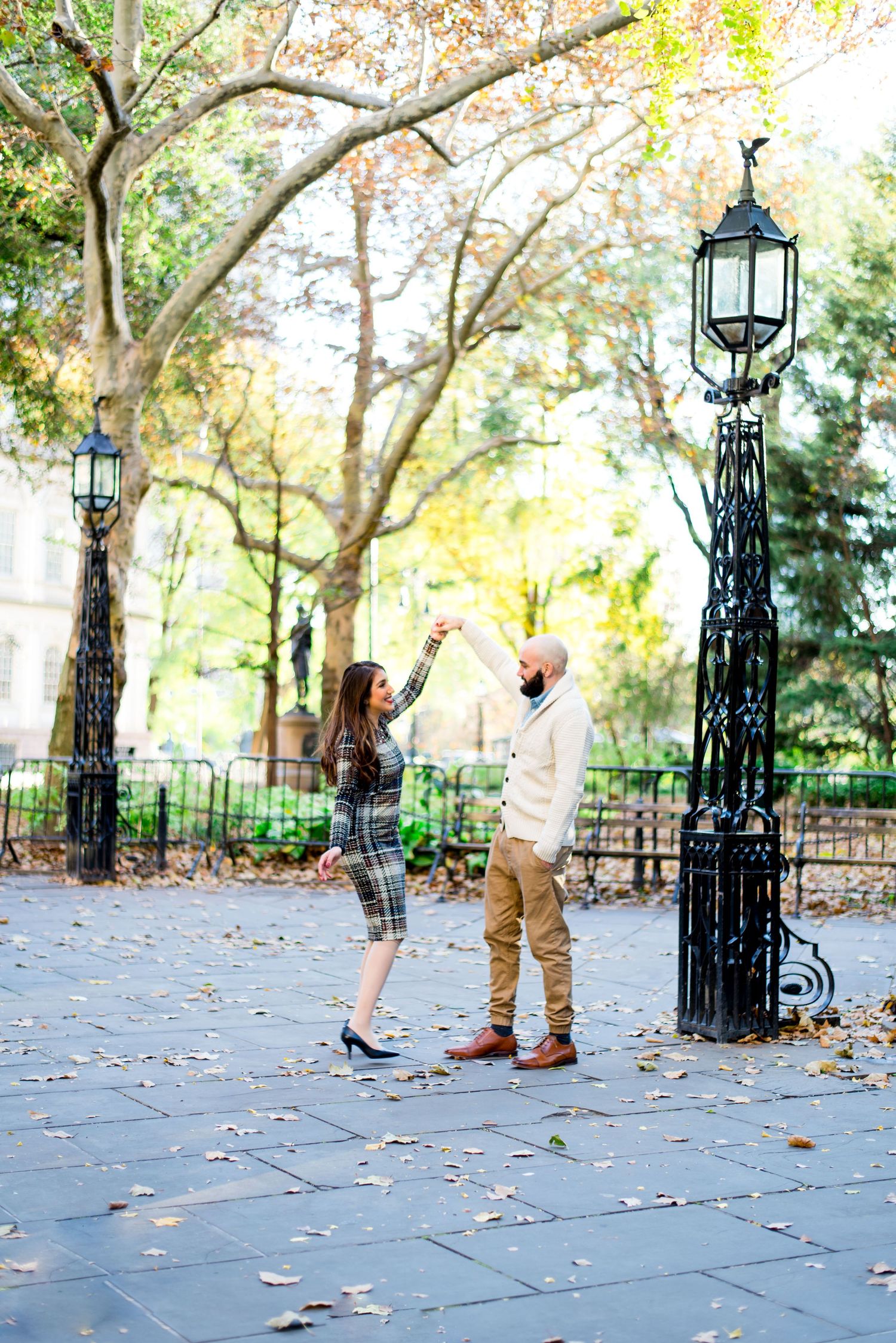 cute young couple spins around during engagement pictures at NYC City Hall in November