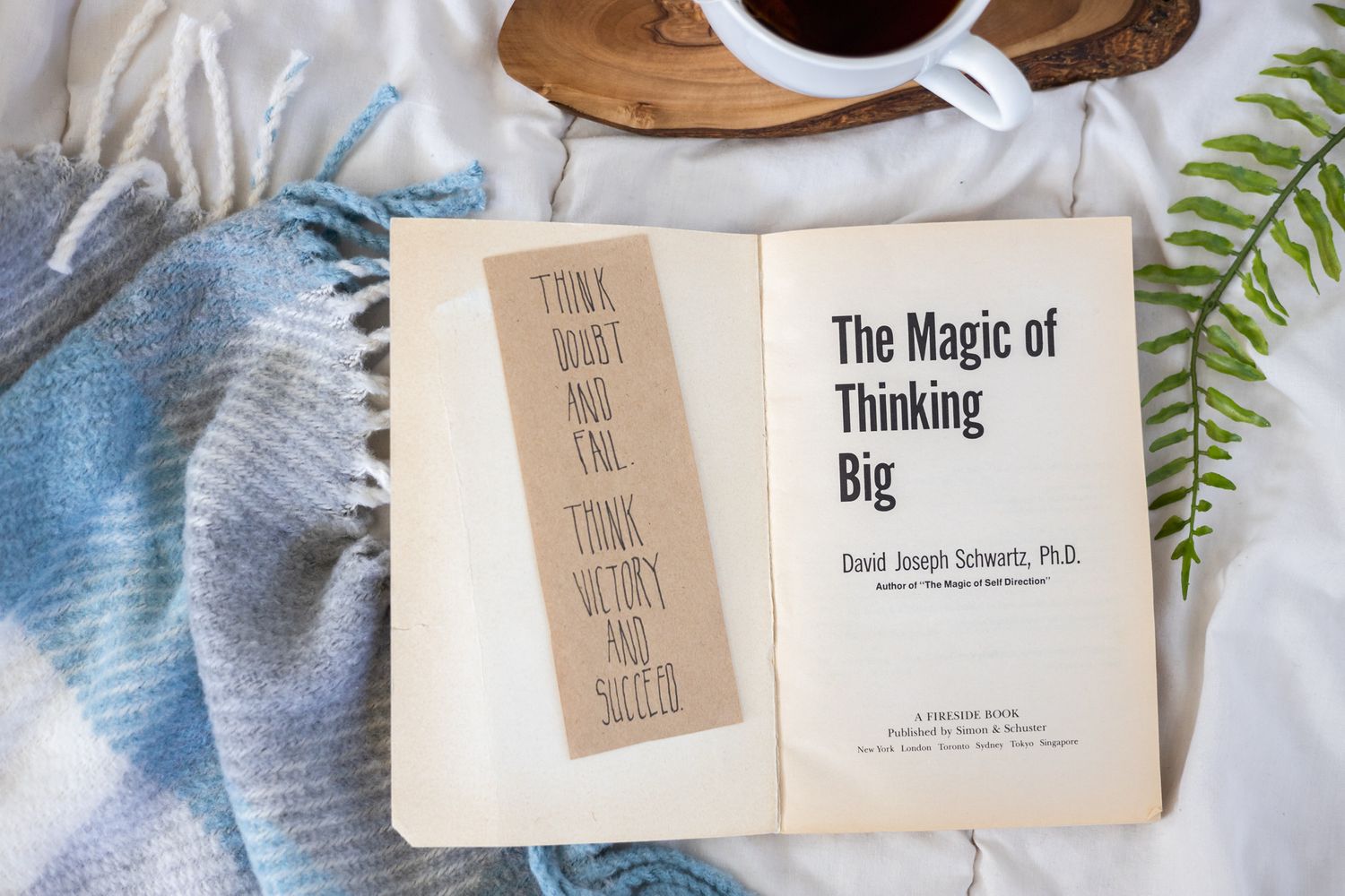self help book list recommendation the magic of thinking big by joseph schwartz phd on blanket with cup of tea and fern