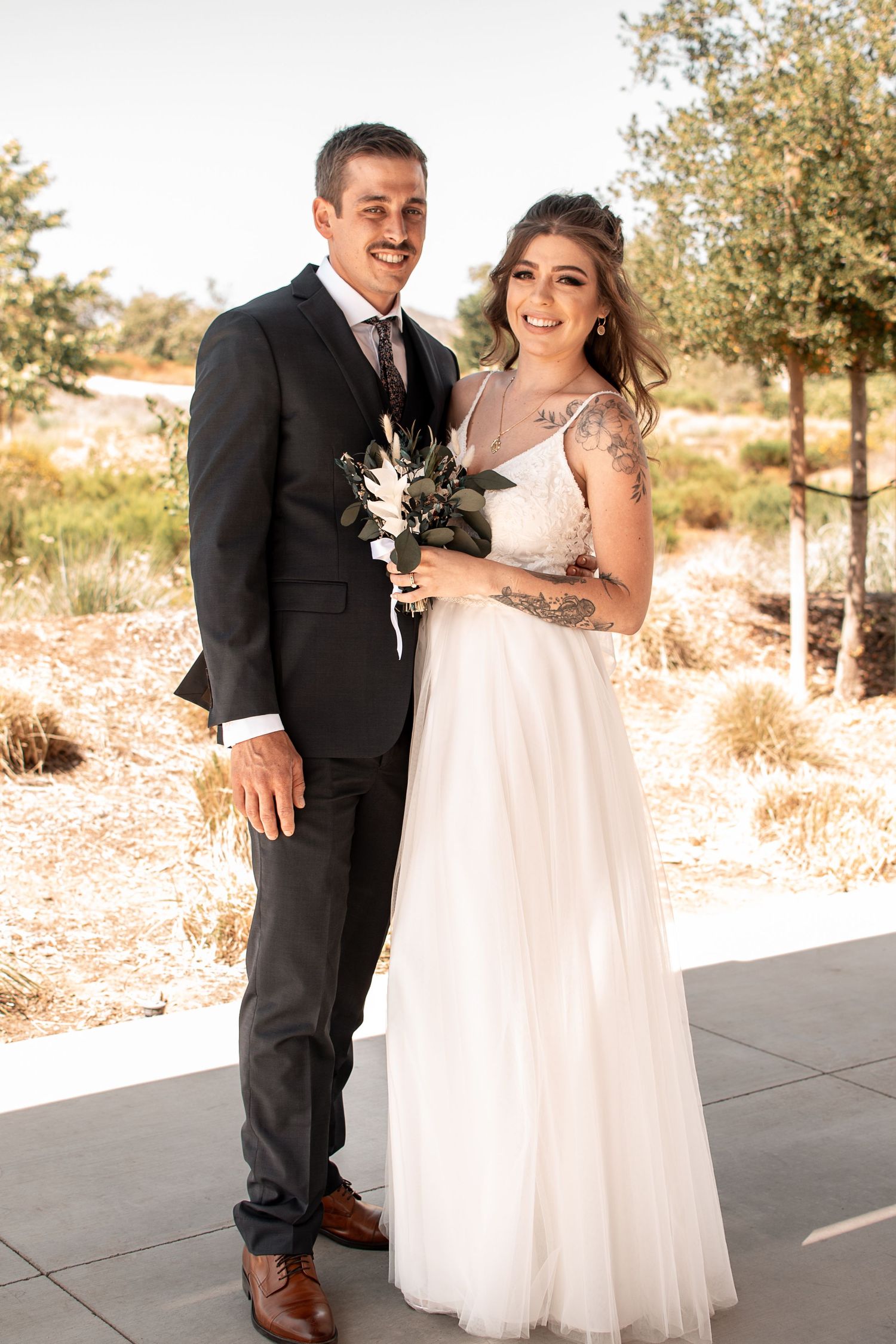 Wedding portrait of newlyweds in formal attire with white bouquet.