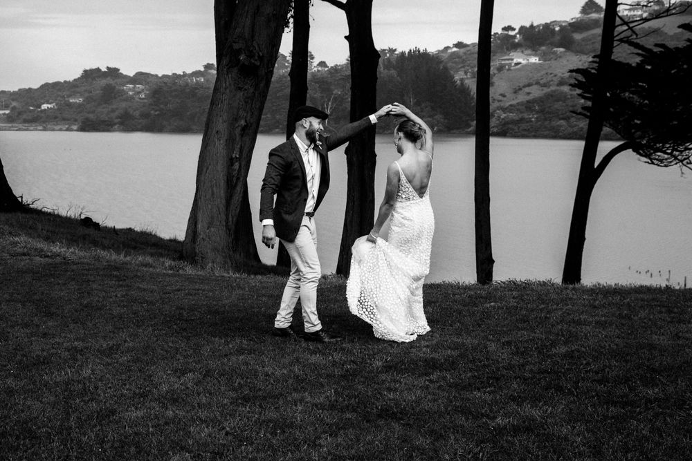 A couple walks together on a grassy hillside overlooking a serene lake.