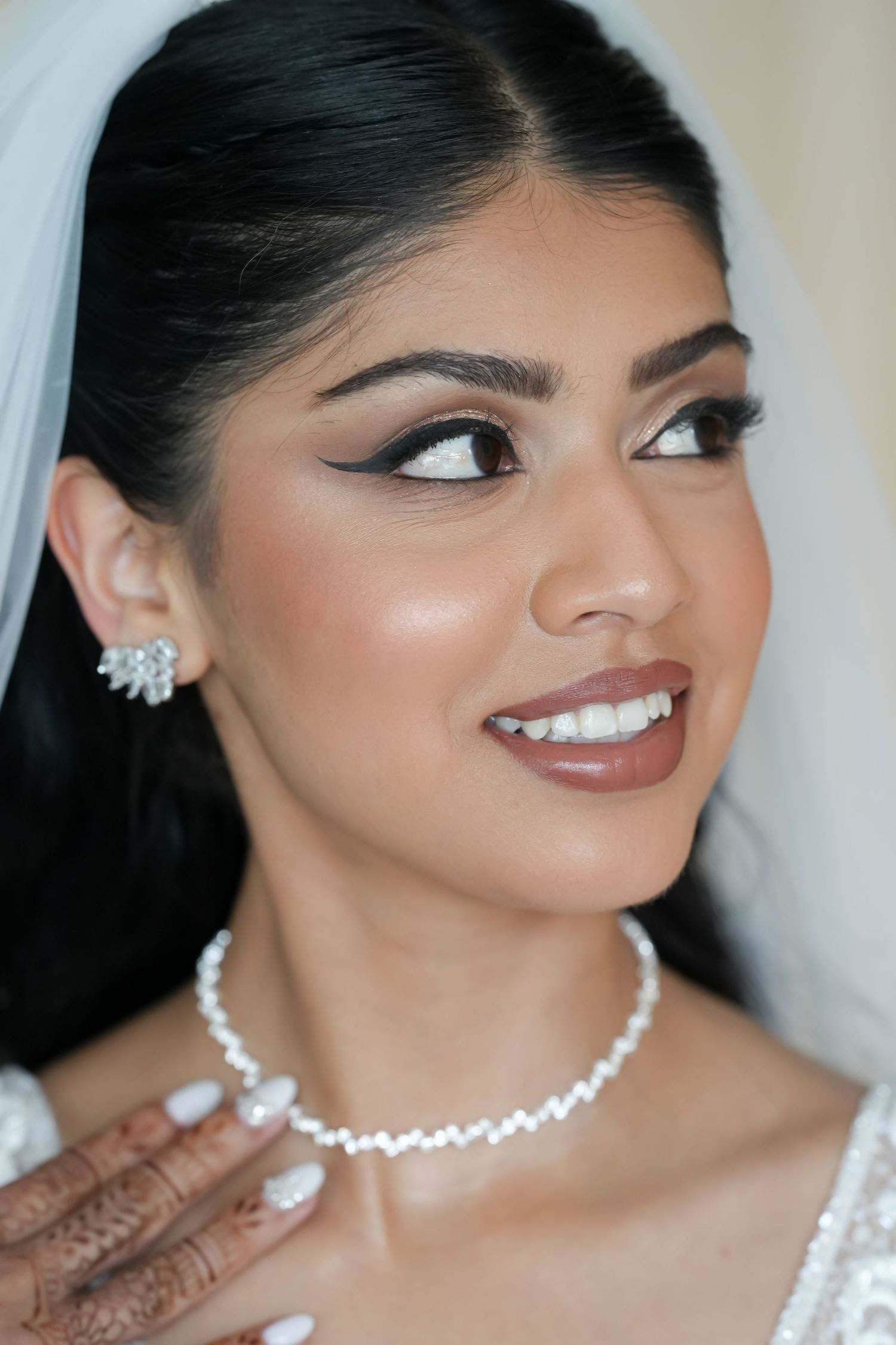 Close-up portrait of bride wearing pearl necklace and crystal earrings with elegant makeup.