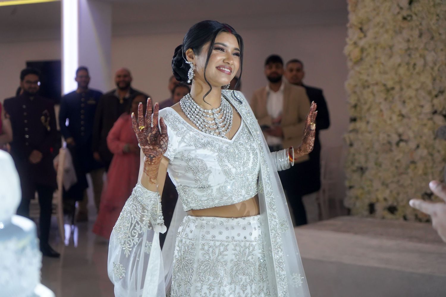 Bride in traditional white two-piece lehenga outfit with detailed embroidery and jewelry.