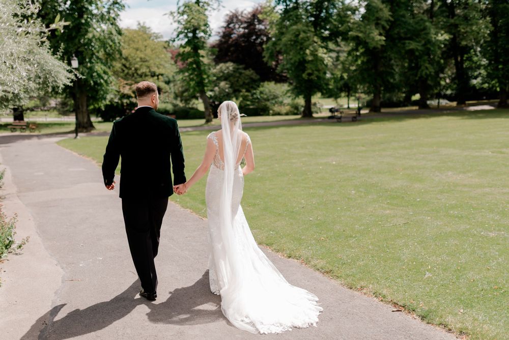 Couple walks hand in hand along garden path after their wedding ceremony.