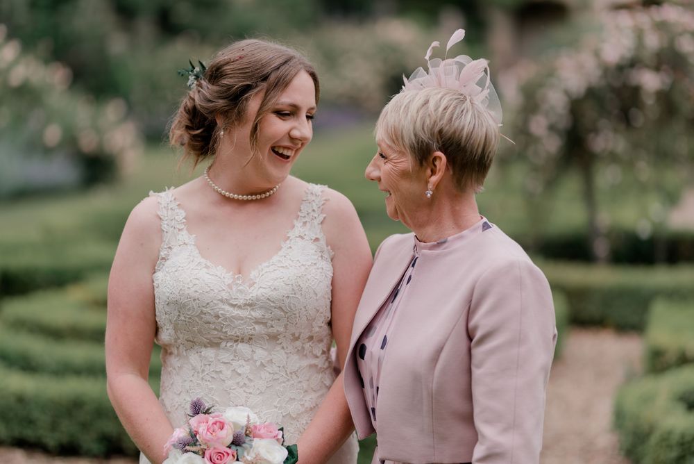 Two people outdoors share a tender moment in a lush garden setting with soft natural lighting.
