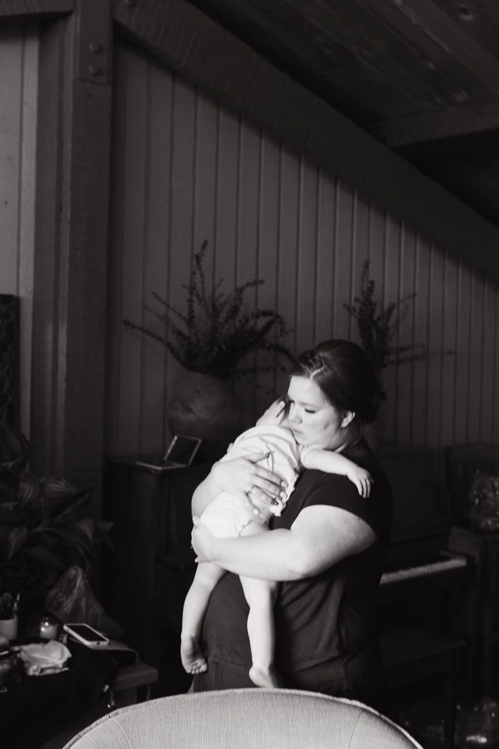 Minnesota indoor wedding venue. Bride with hair and makeup done standing and holding little girl. Black and White