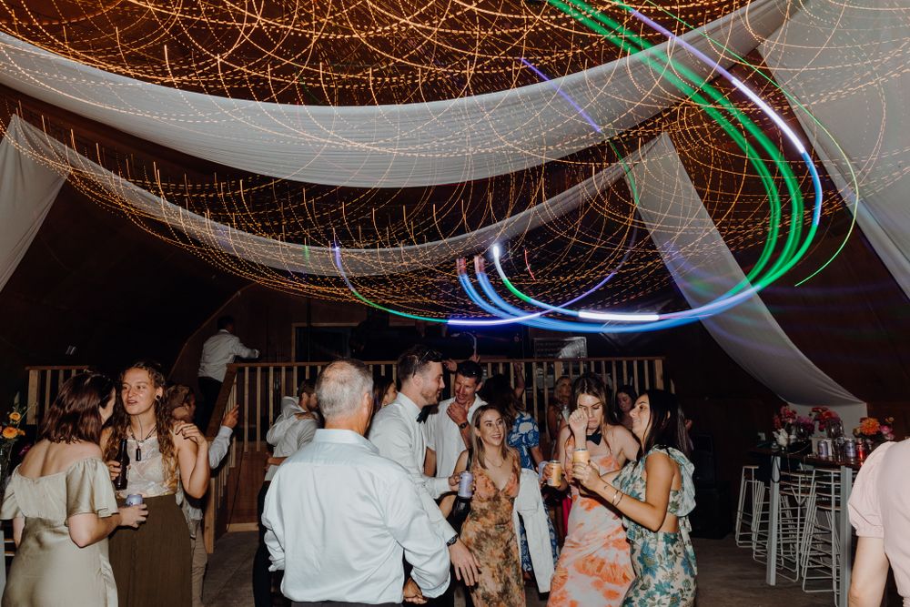 Wedding reception venue decorated with white drapery and colorful LED light installations.