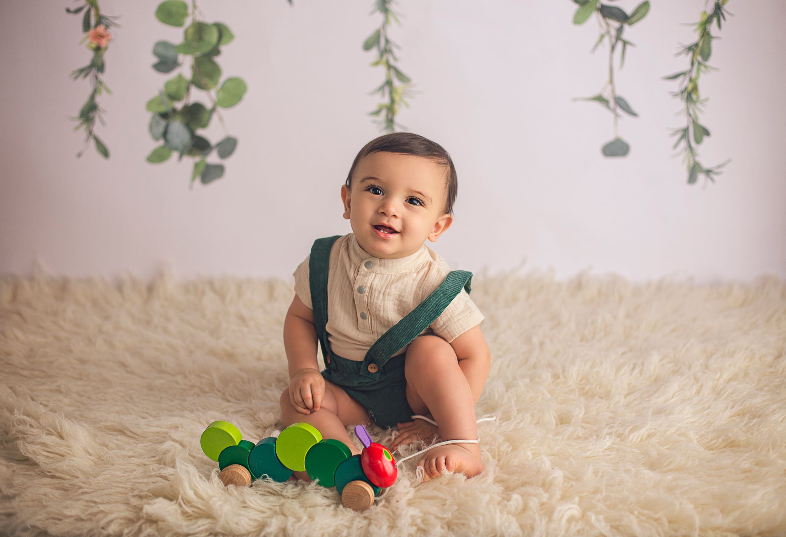 happy baby boy 9 months old with green suspenders
