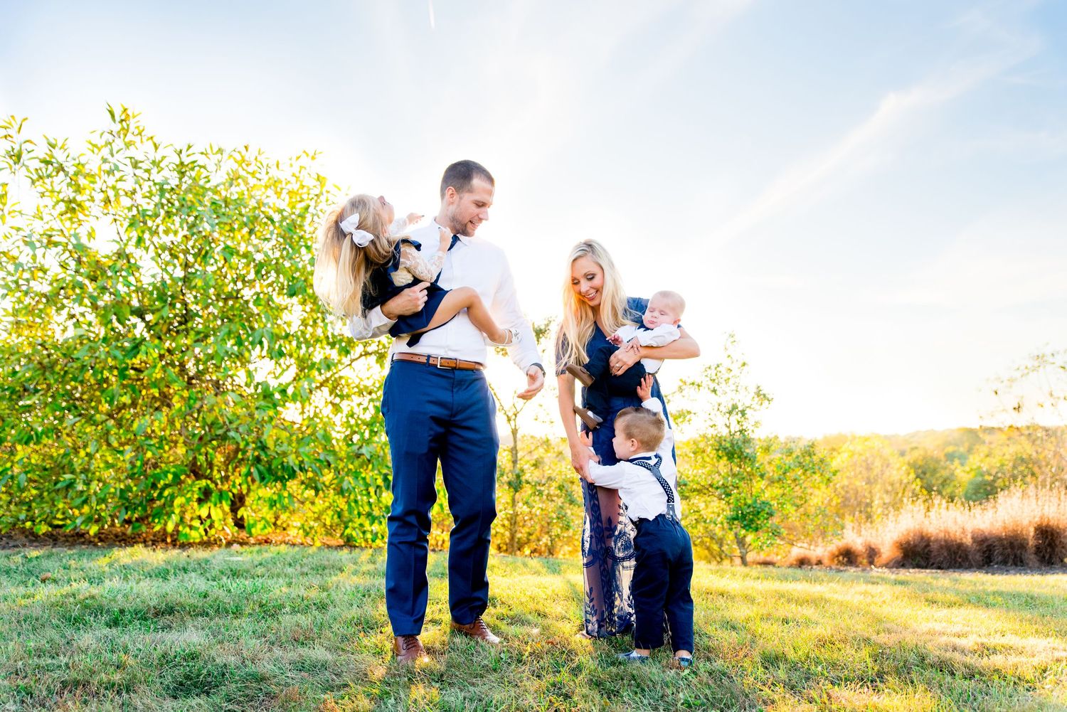 family of five wearing navy and white clothes laughing and talking to each other under the blue skies with clouds