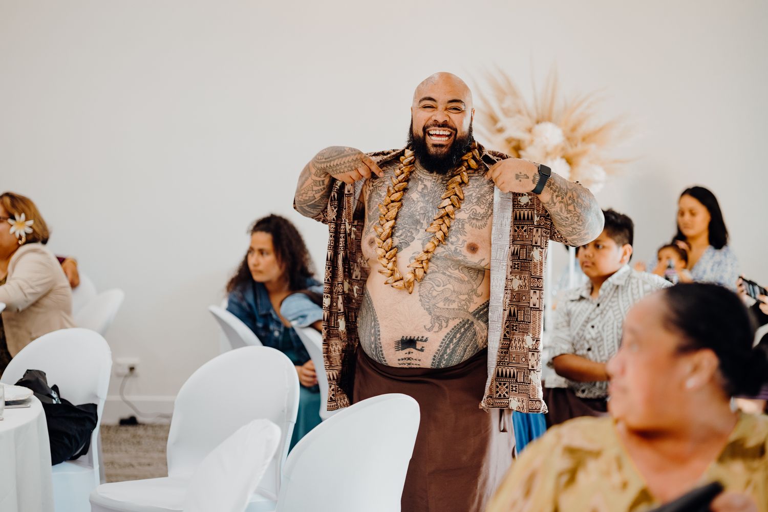 Wedding performer wearing brown outfit and lei performs for seated guests.