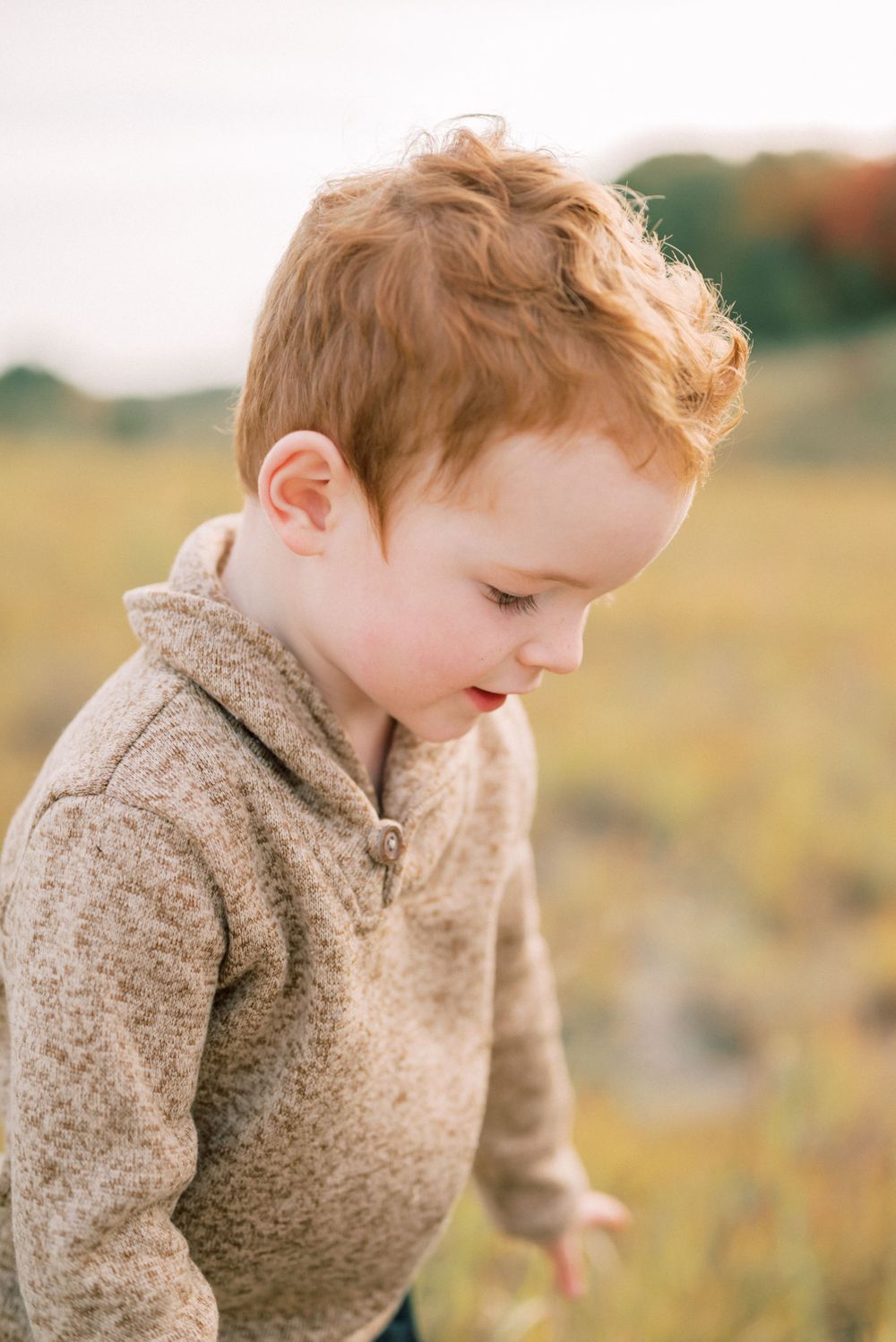 Close-up portrait of a child wearing a cozy sweater in an autumn field.