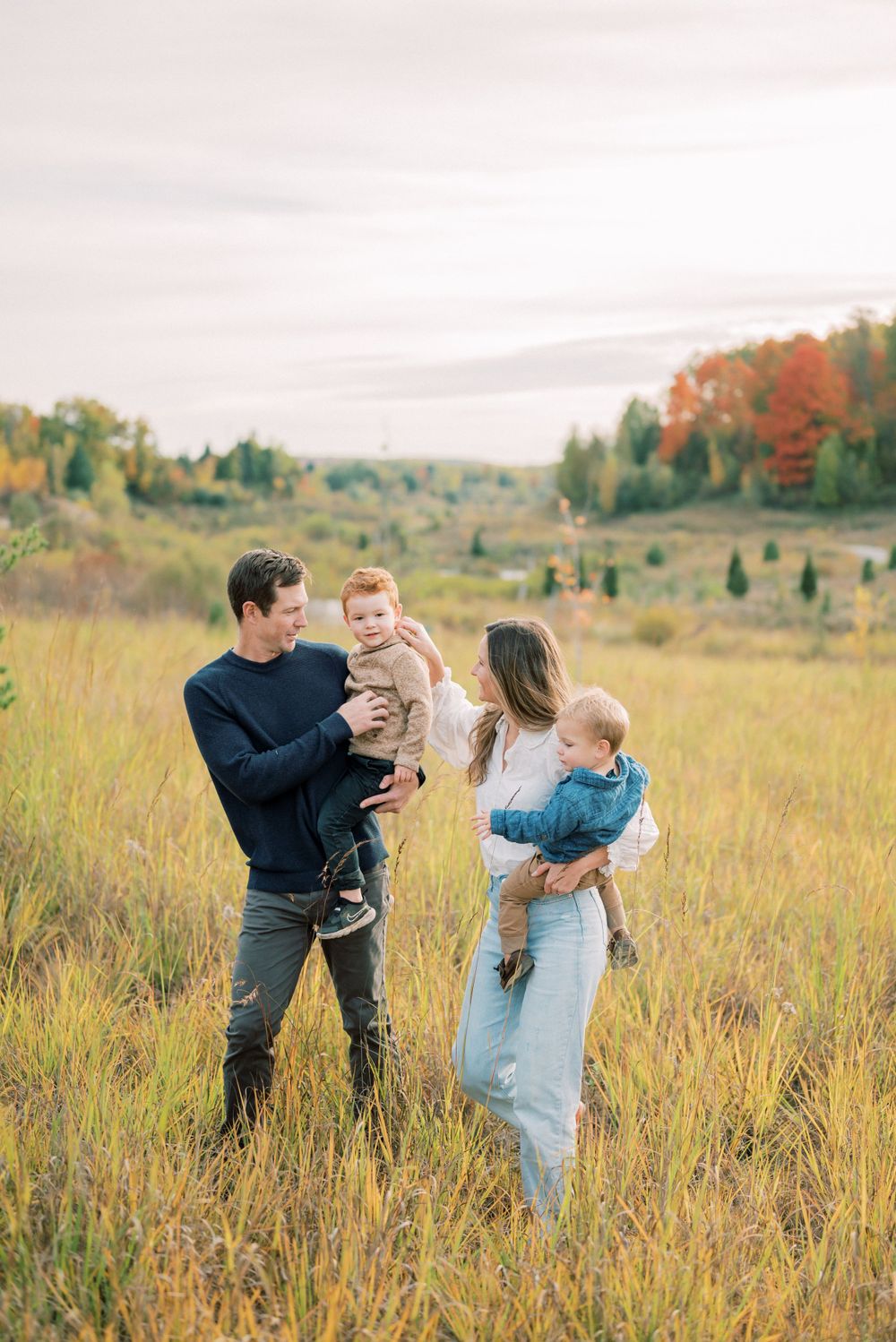 A family sharing a tender moment together in a field of tall autumn grass.