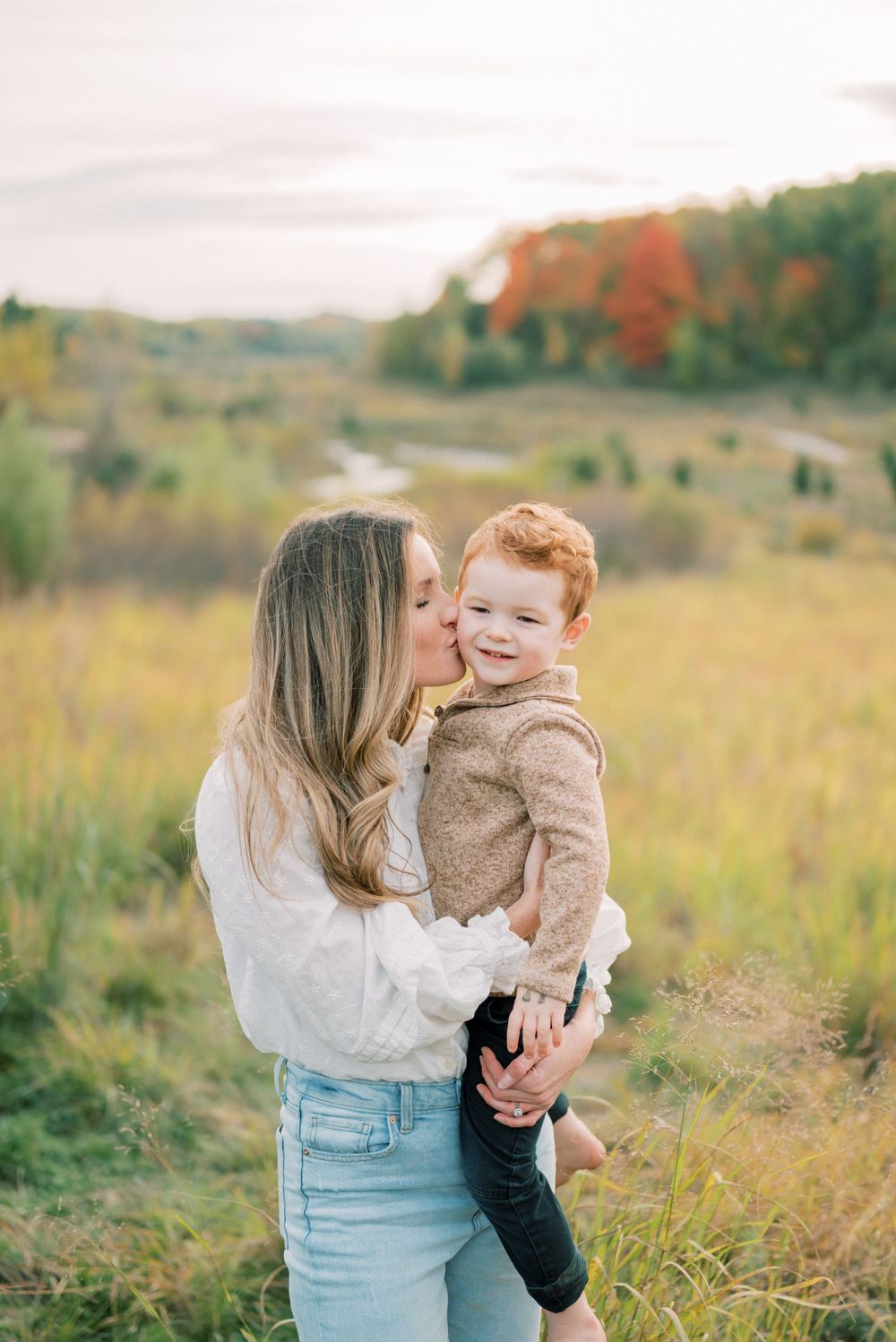 Sweet candid moment between parent and child in a golden autumn meadow.