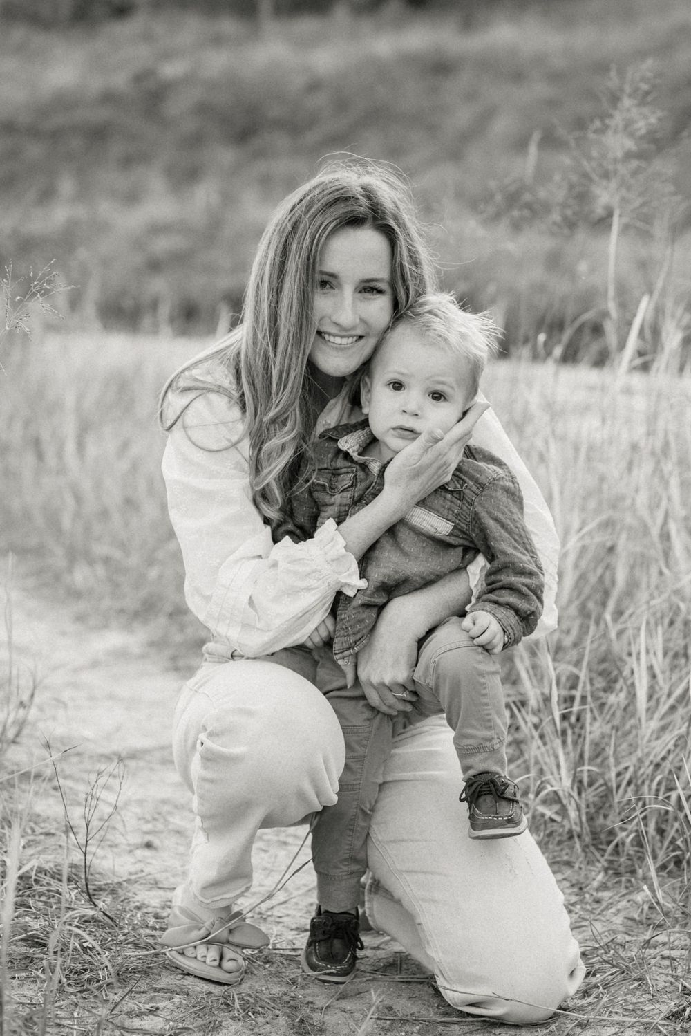 A tender black and white portrait in a natural outdoor setting with tall grass.
