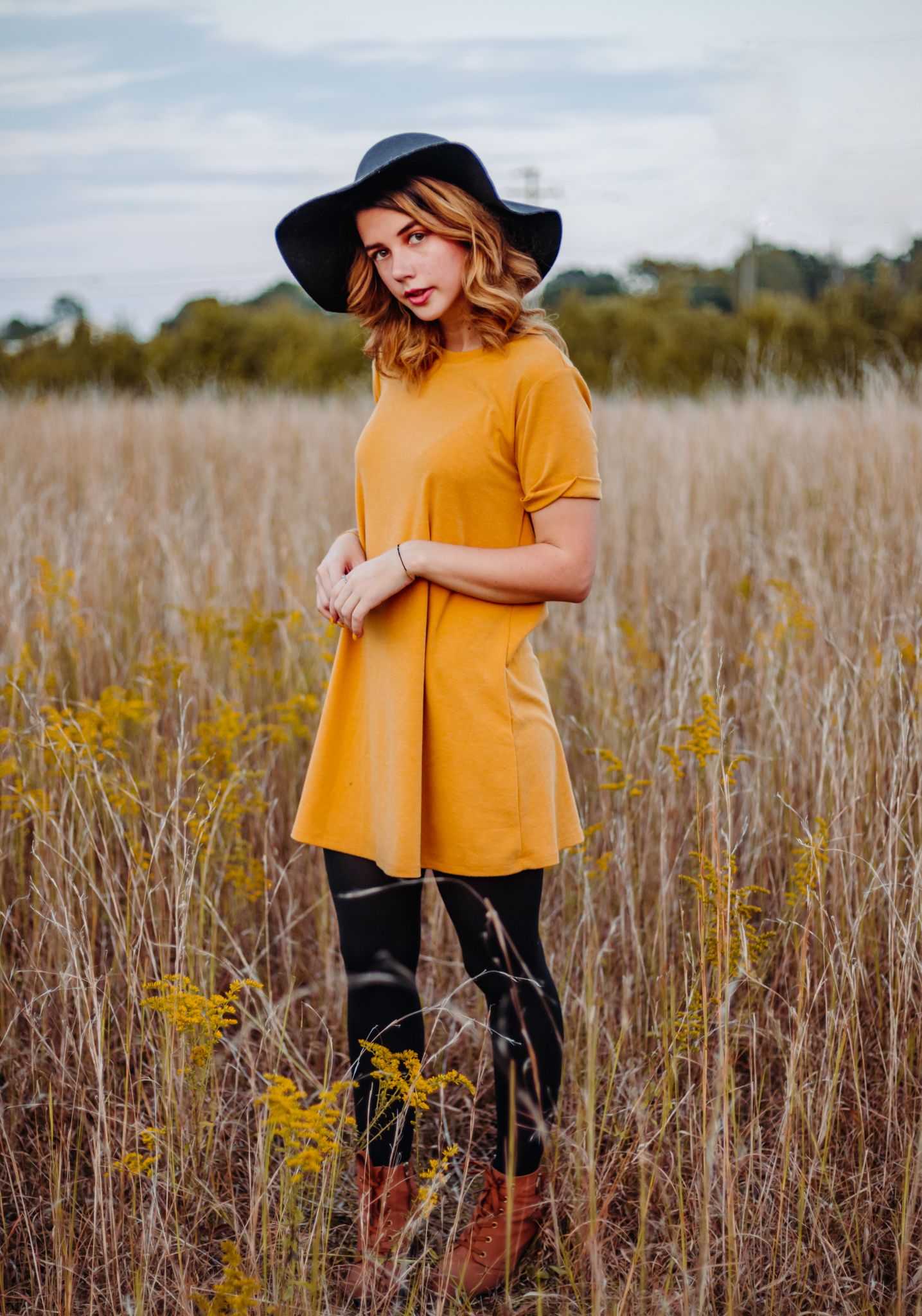 Girl in a yellow dress standing in a field with yellow flowers