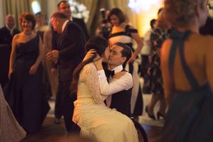 A couple shares an intimate dance moment at a dimly lit wedding reception surrounded by guests.