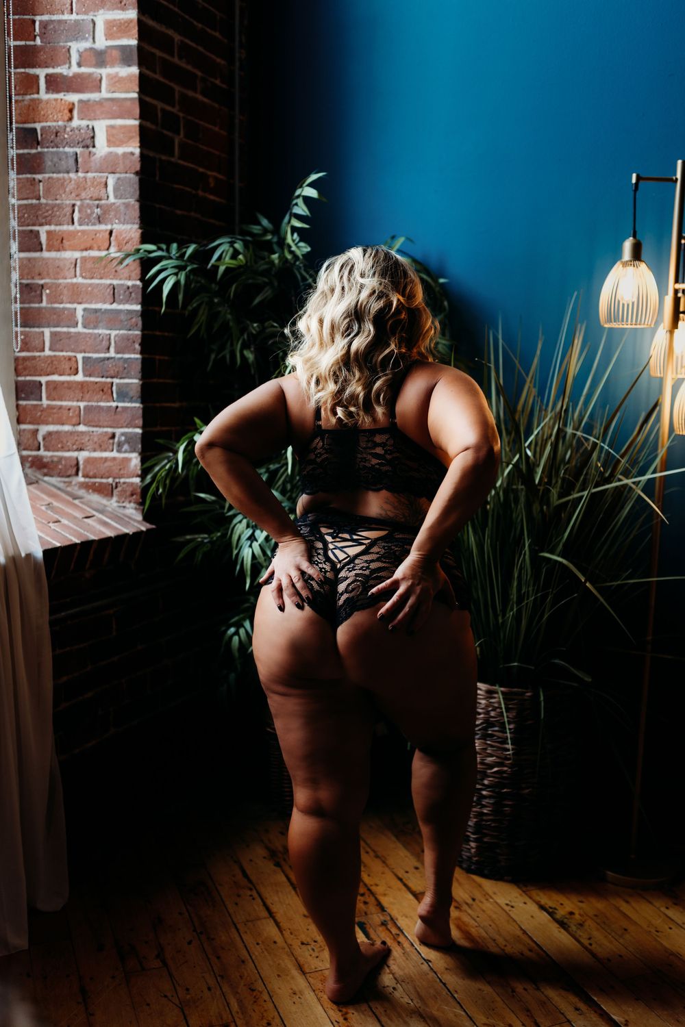 Intimate portrait against brick wall and blue backdrop with indoor plants.