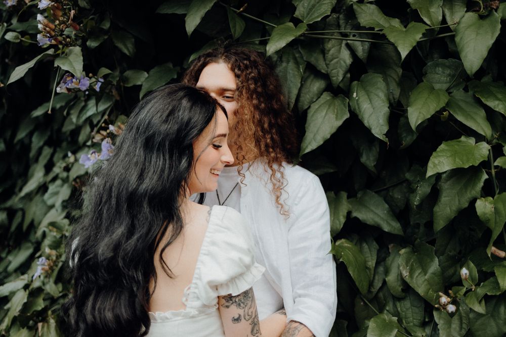 A romantic moment captured against a backdrop of green climbing vines on a brick wall.