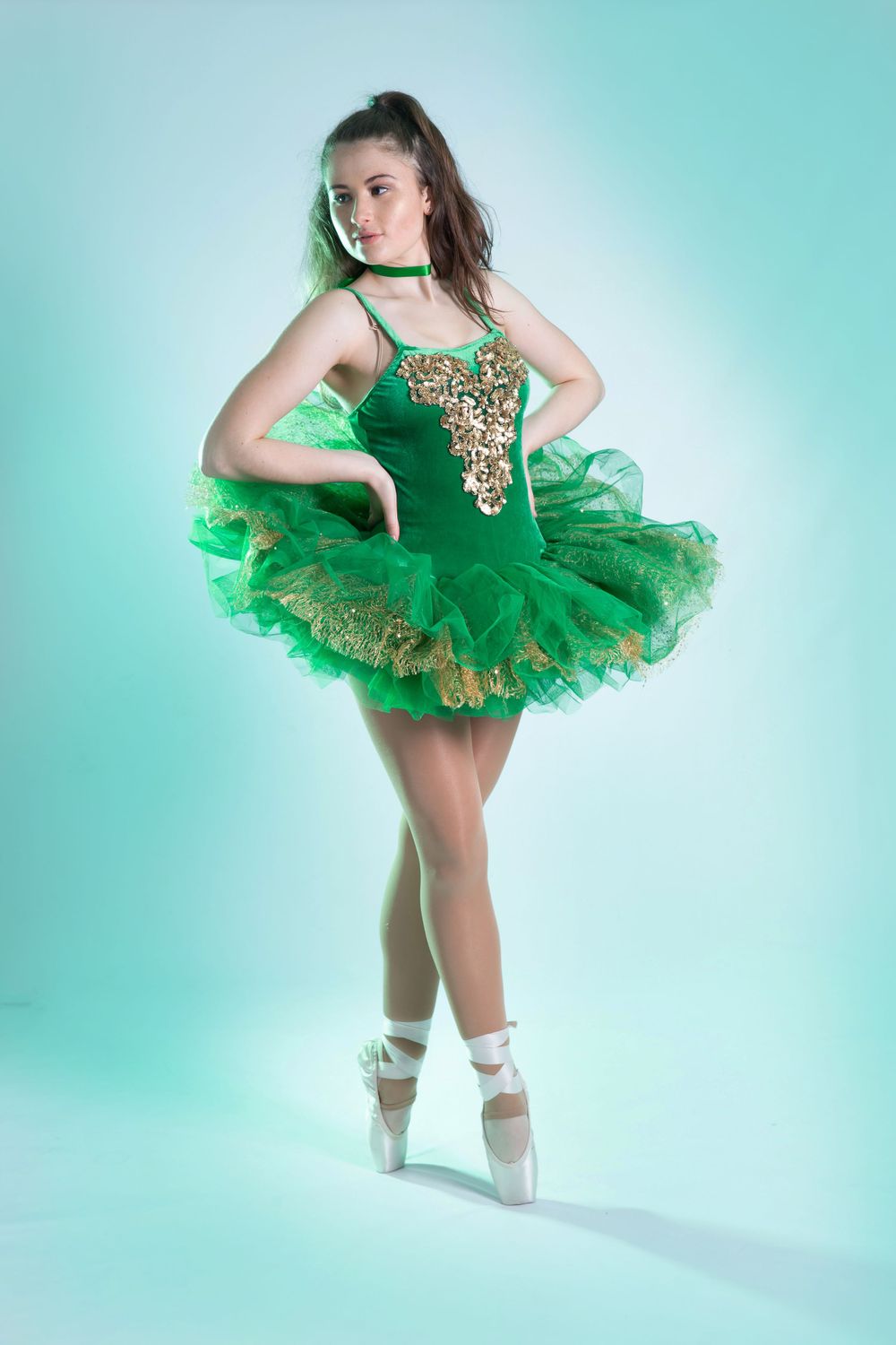 female dancer in green tutu en-pointe with green light background