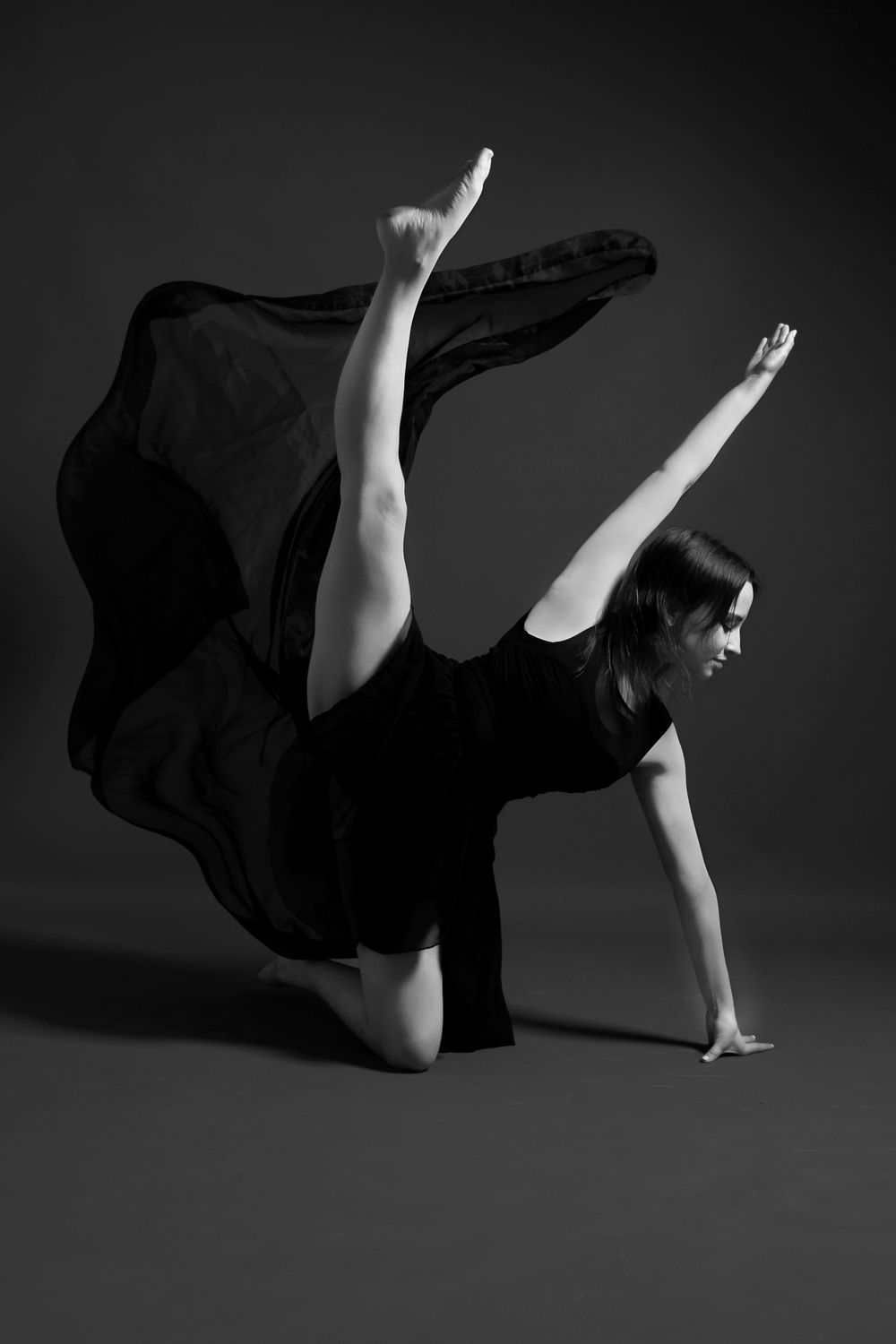 black and white photo of female dancer kneeling with leg raised