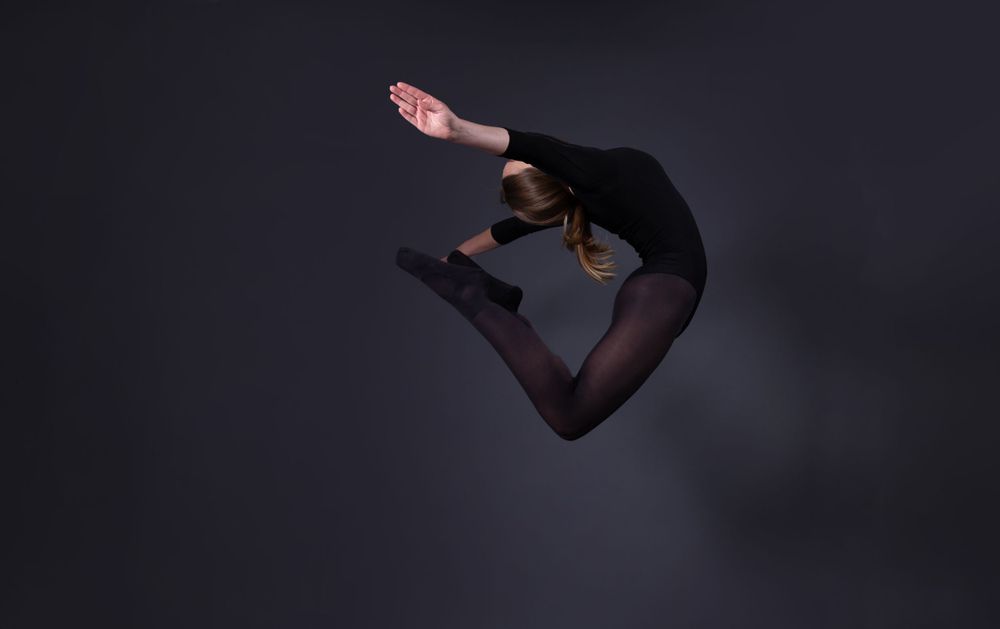 female dancer in black leotard and tights C jump in air