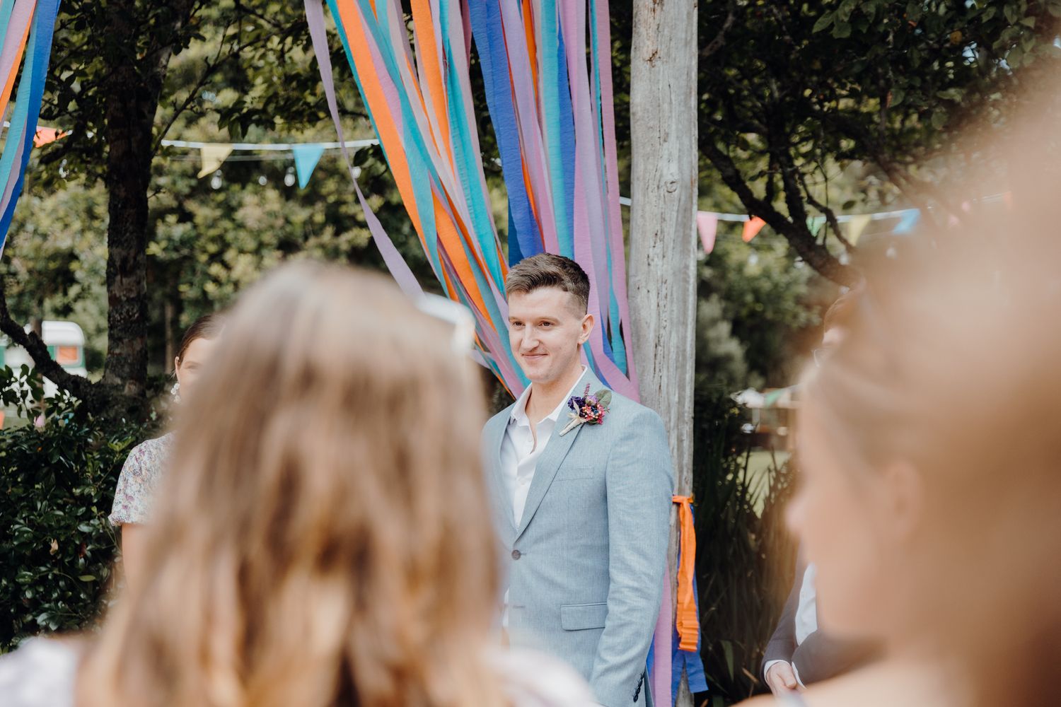 Wedding ceremony with light blue decorative streamers and natural outdoor setting.