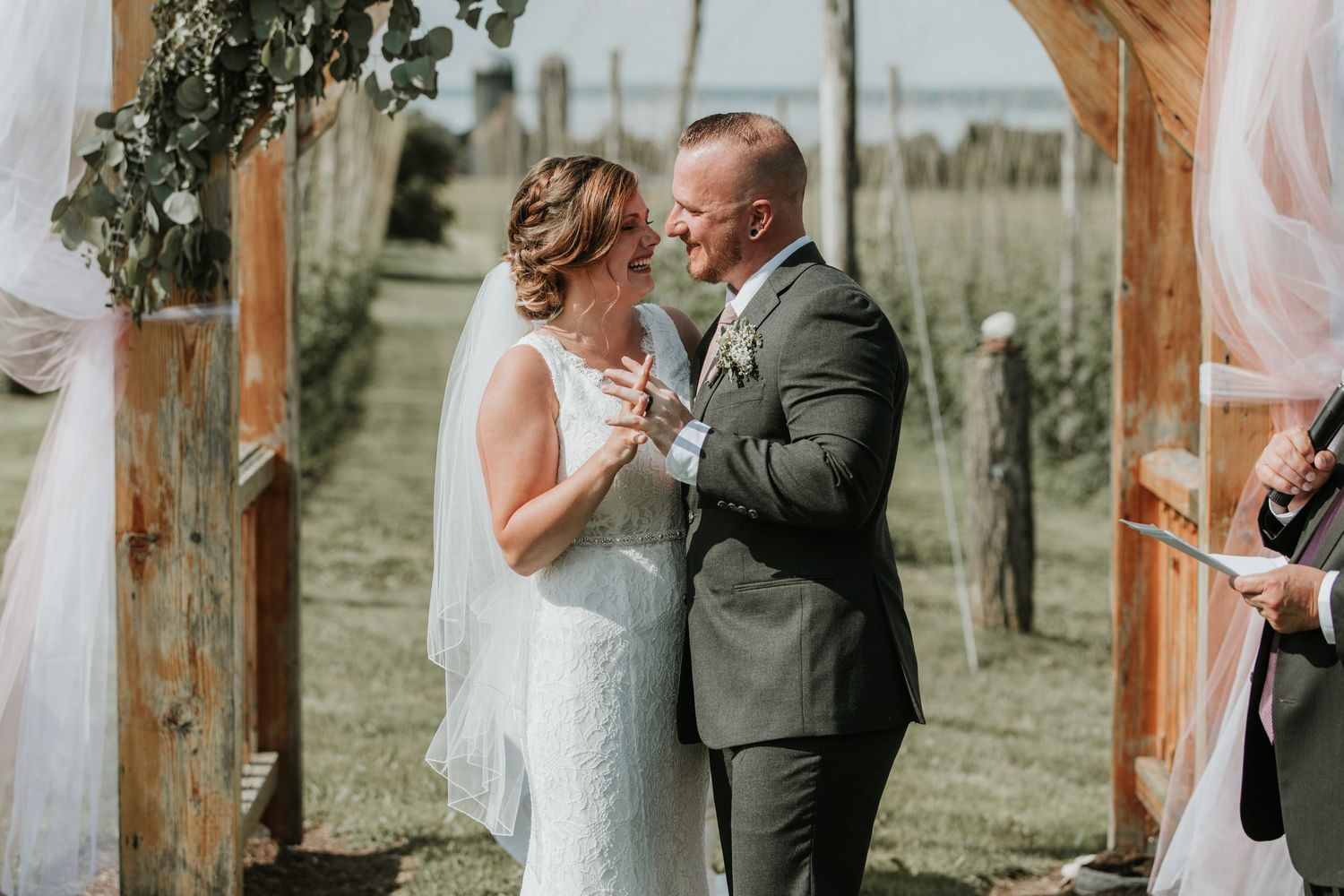 bride and groom smiling at each other at the alter with Seneca Lake behind them