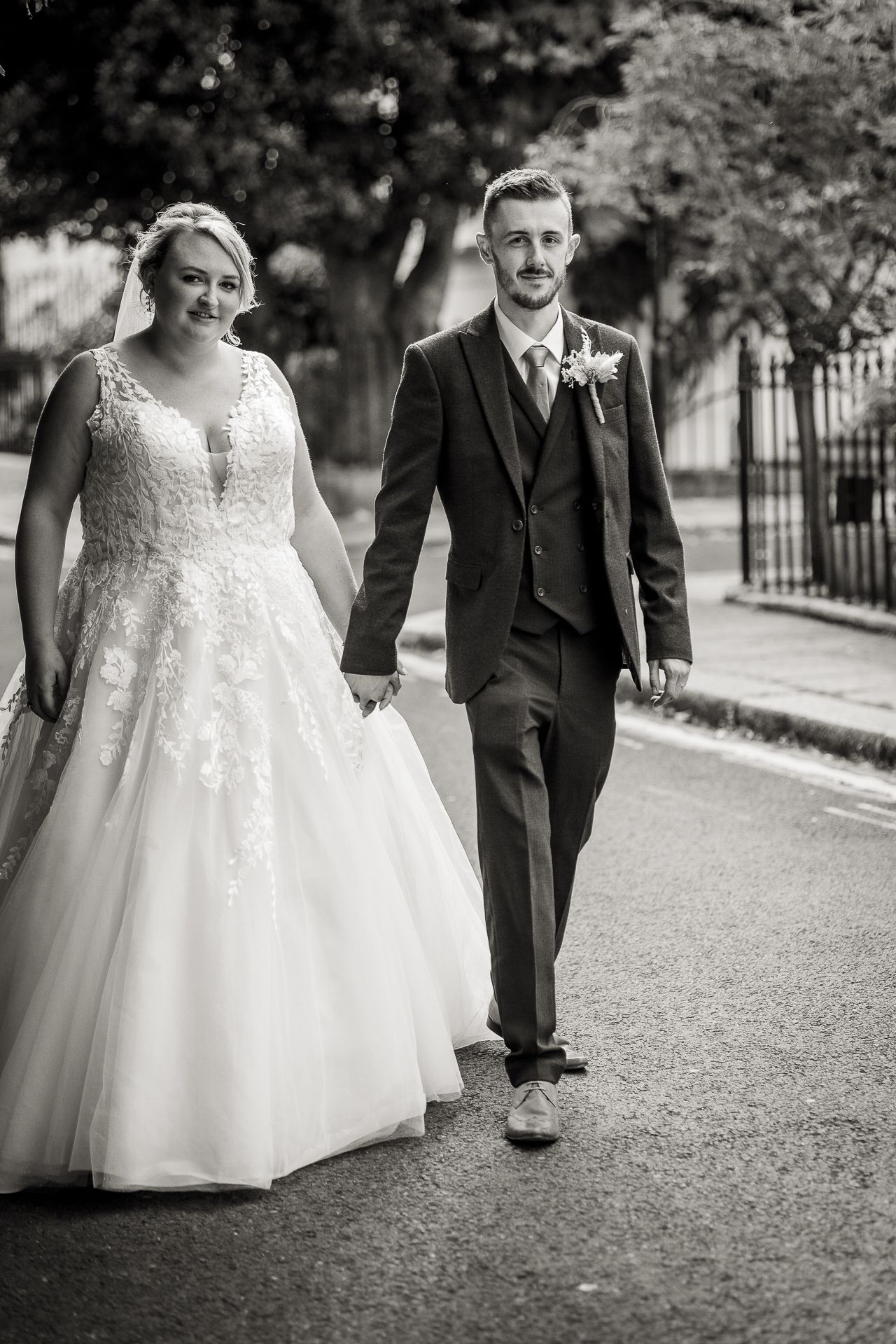 Black and white photography of bride and groom walking and holding hands in Chelsea, London