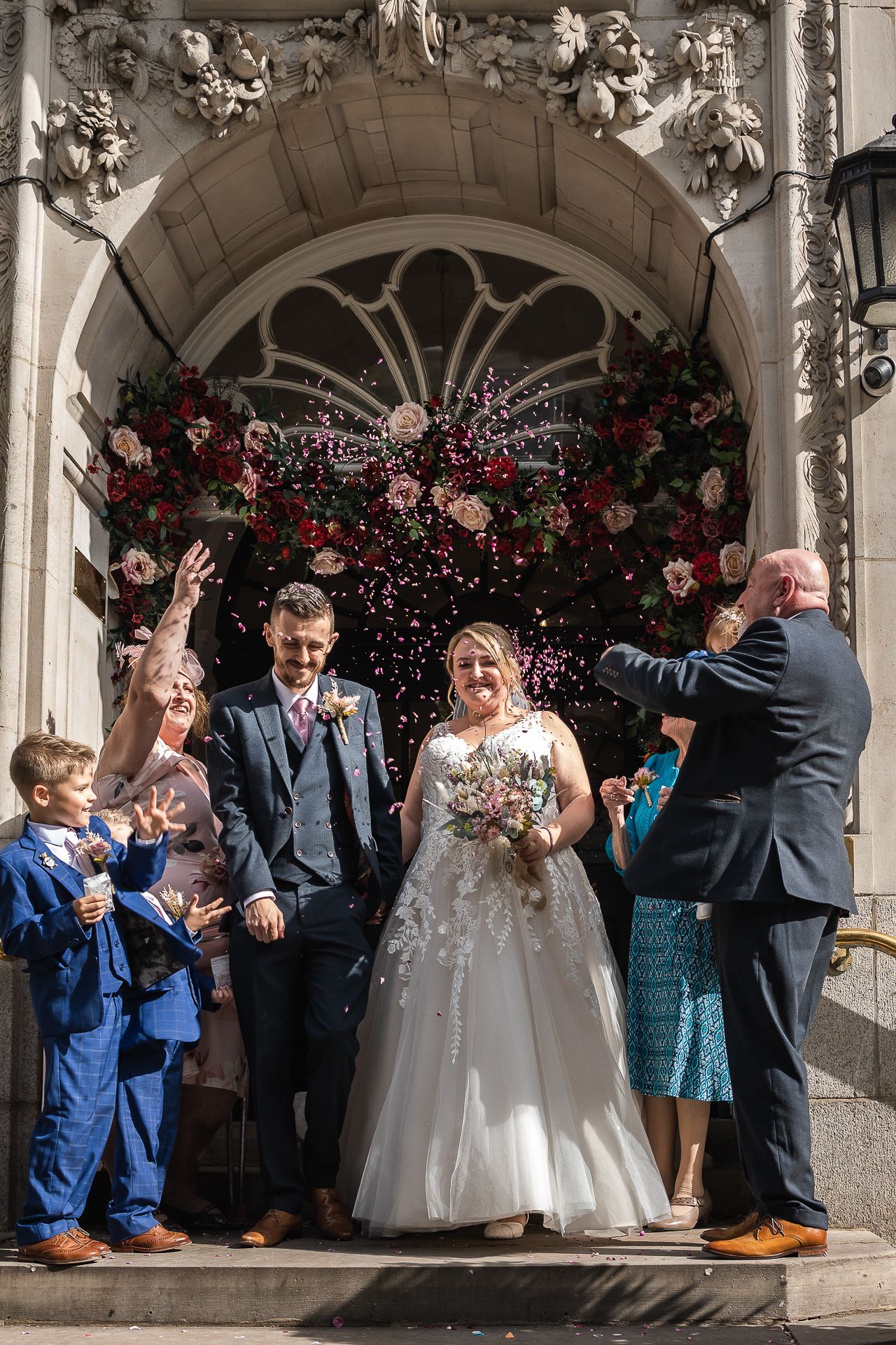 Confetti shot of wedding couple and their family on the steps of Chelsea Old town Hall