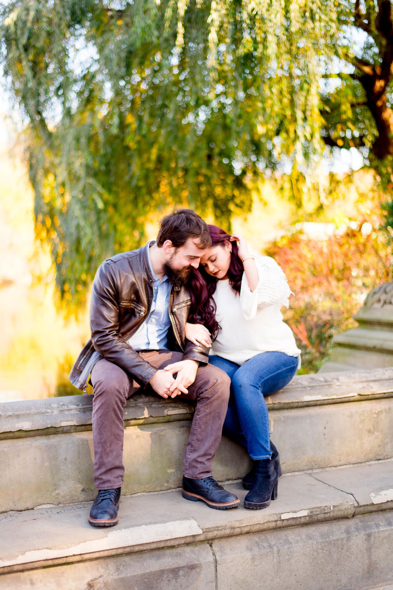 engaged man and woman sitting by the pond at Central Park for fall engagement pictures