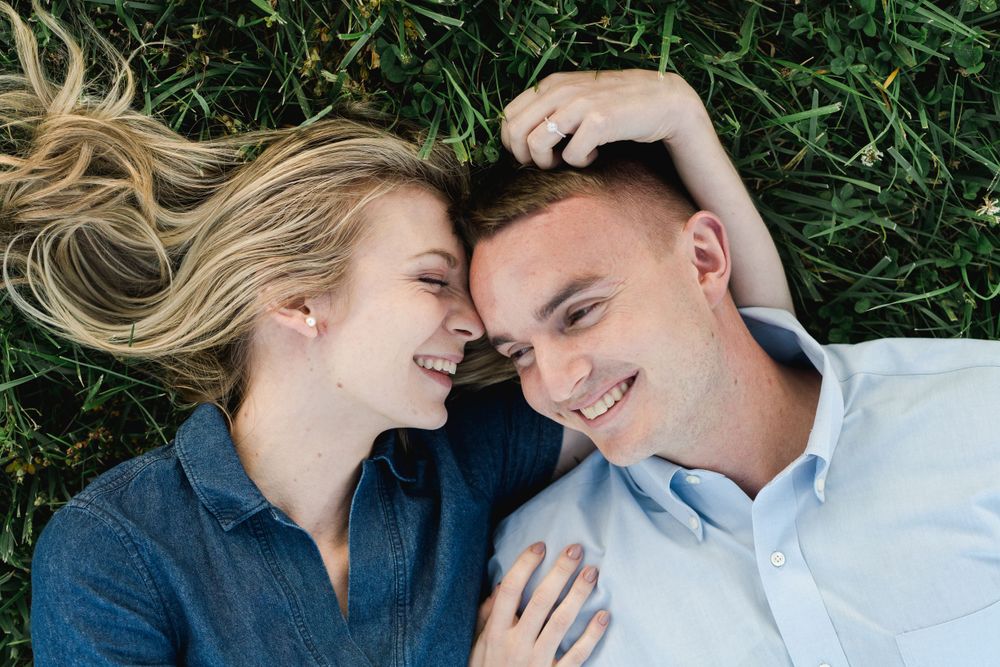 Newly engaged couple laughing in the grass