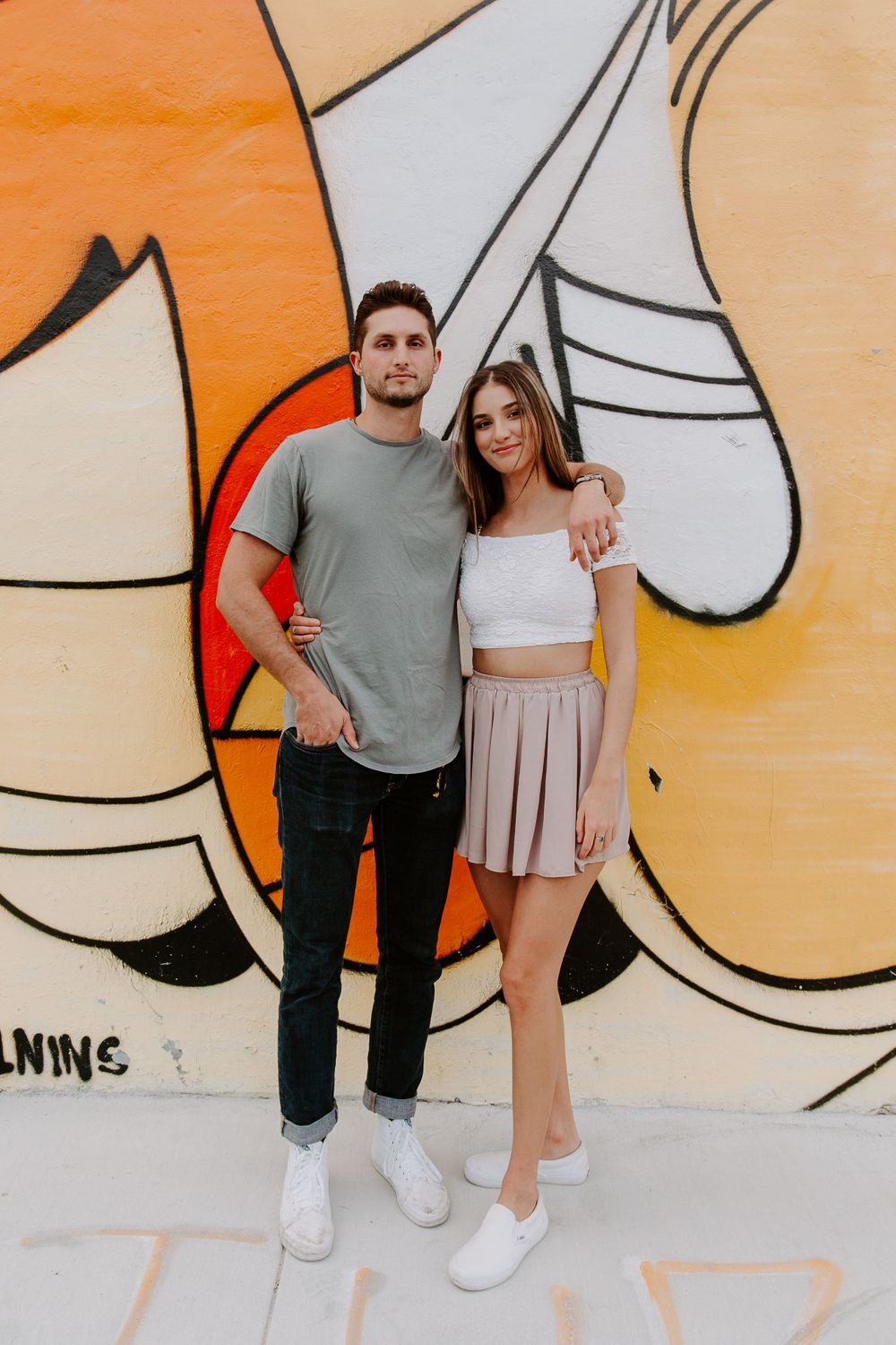 smiling couple in front of wall mural in Miami