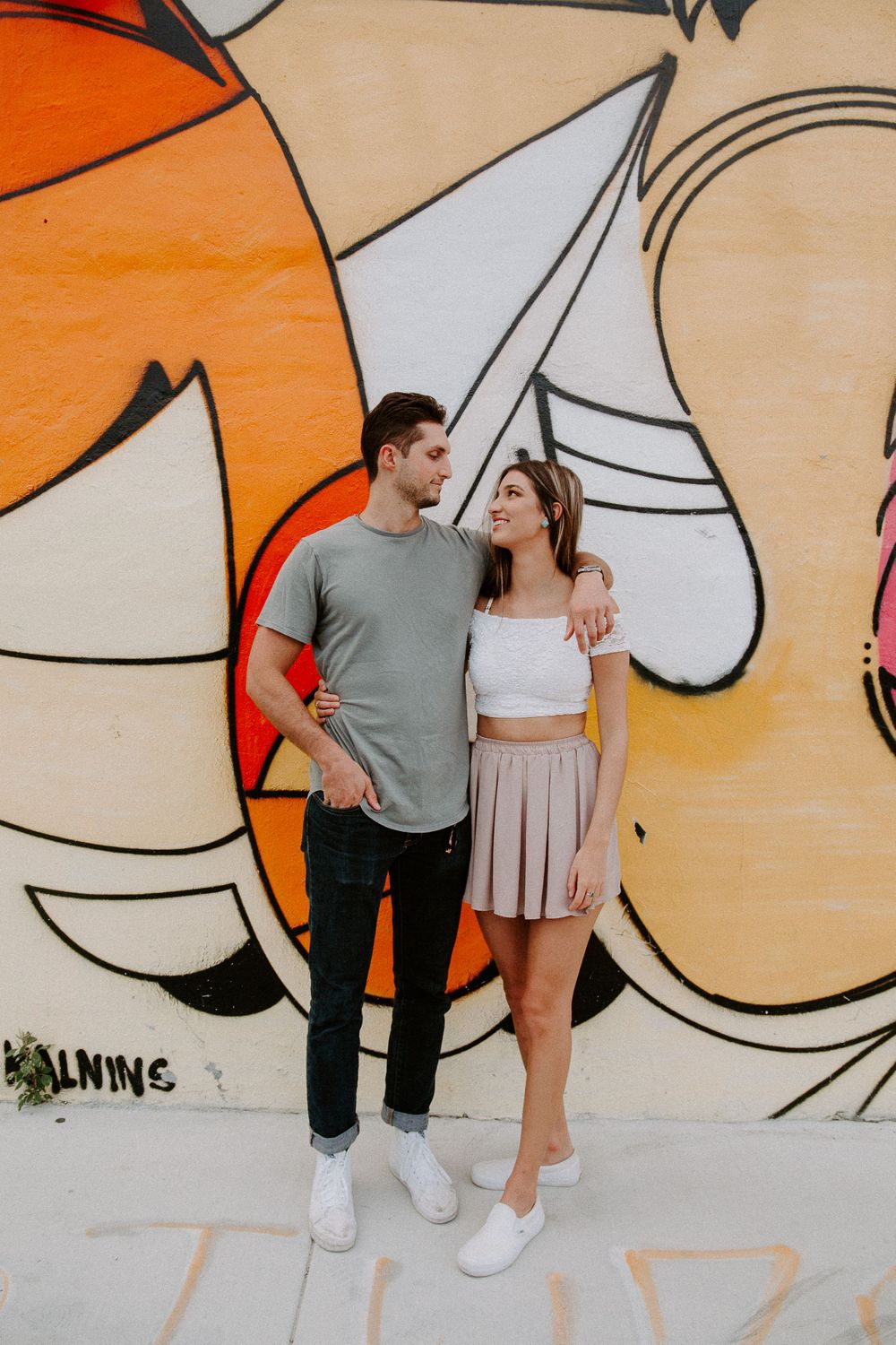 couple looking at each other in front of Miami murals