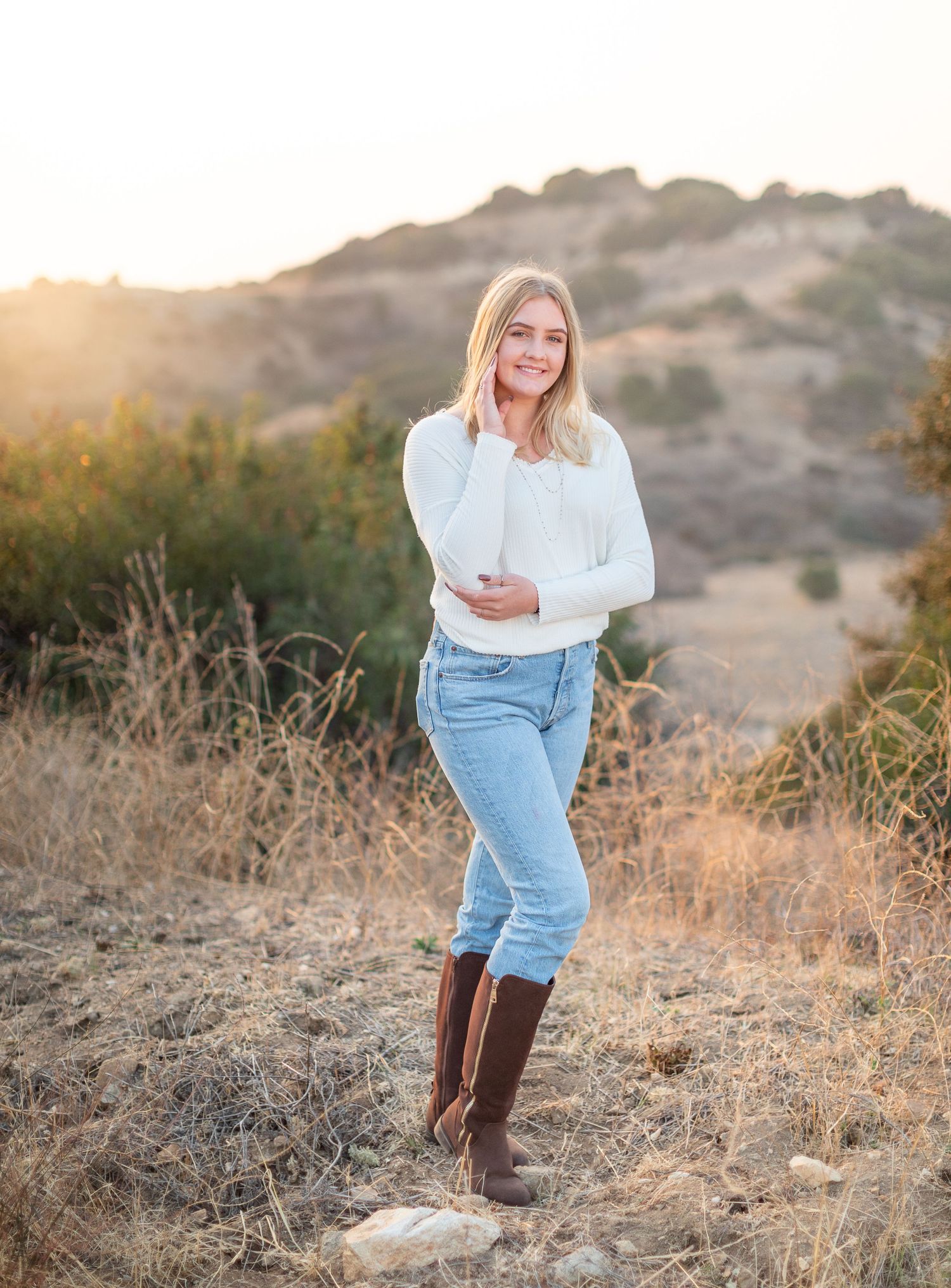 Blonde teen in cream sweater with boots outdoors