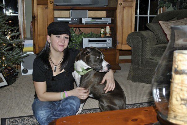 A girl sitting on the floor with her black and white pitbull dog