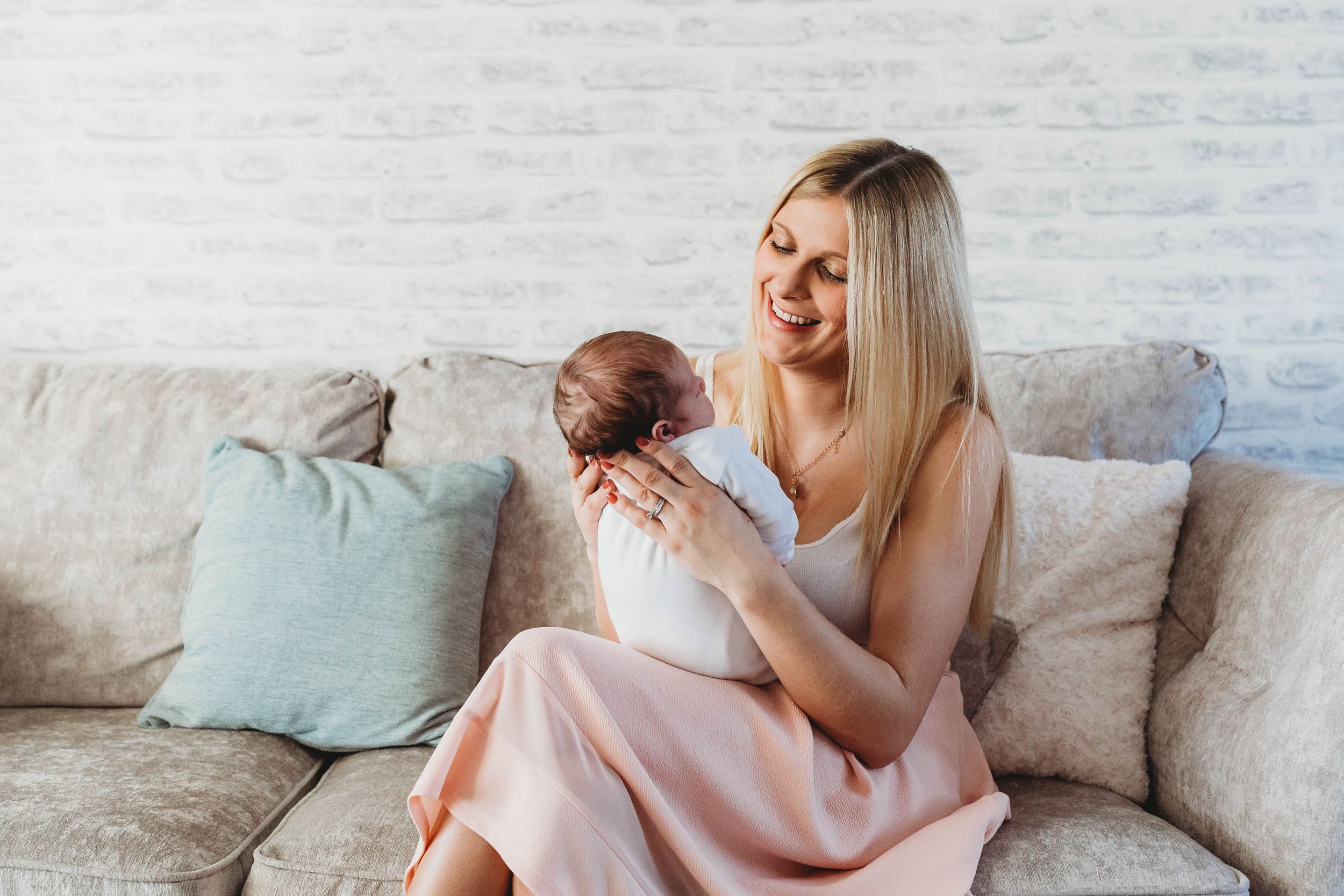 blonde woman holding newborn baby girl smiling