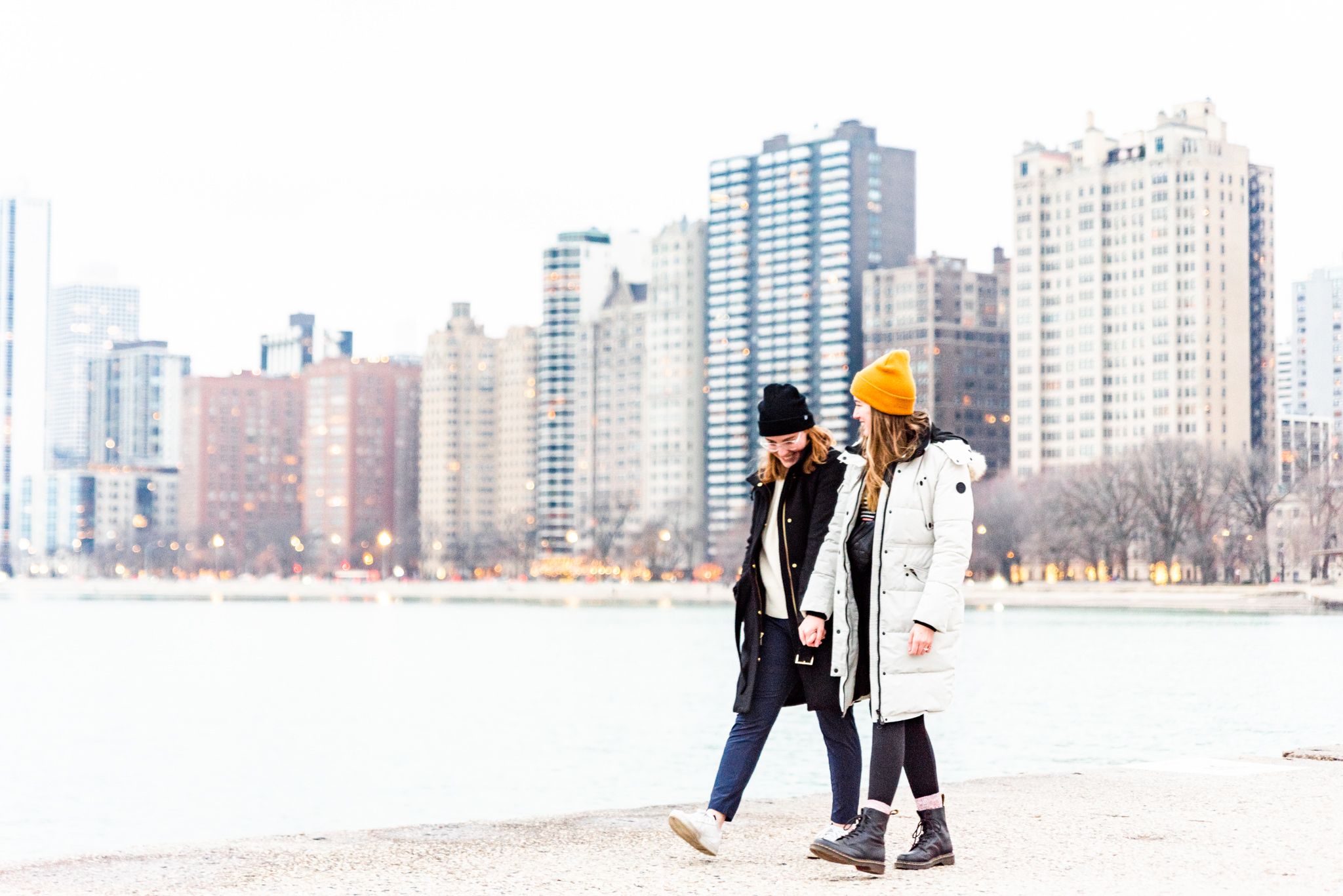 lesbian couple walking along pier at North Avenue Beach after proposal in Chicago