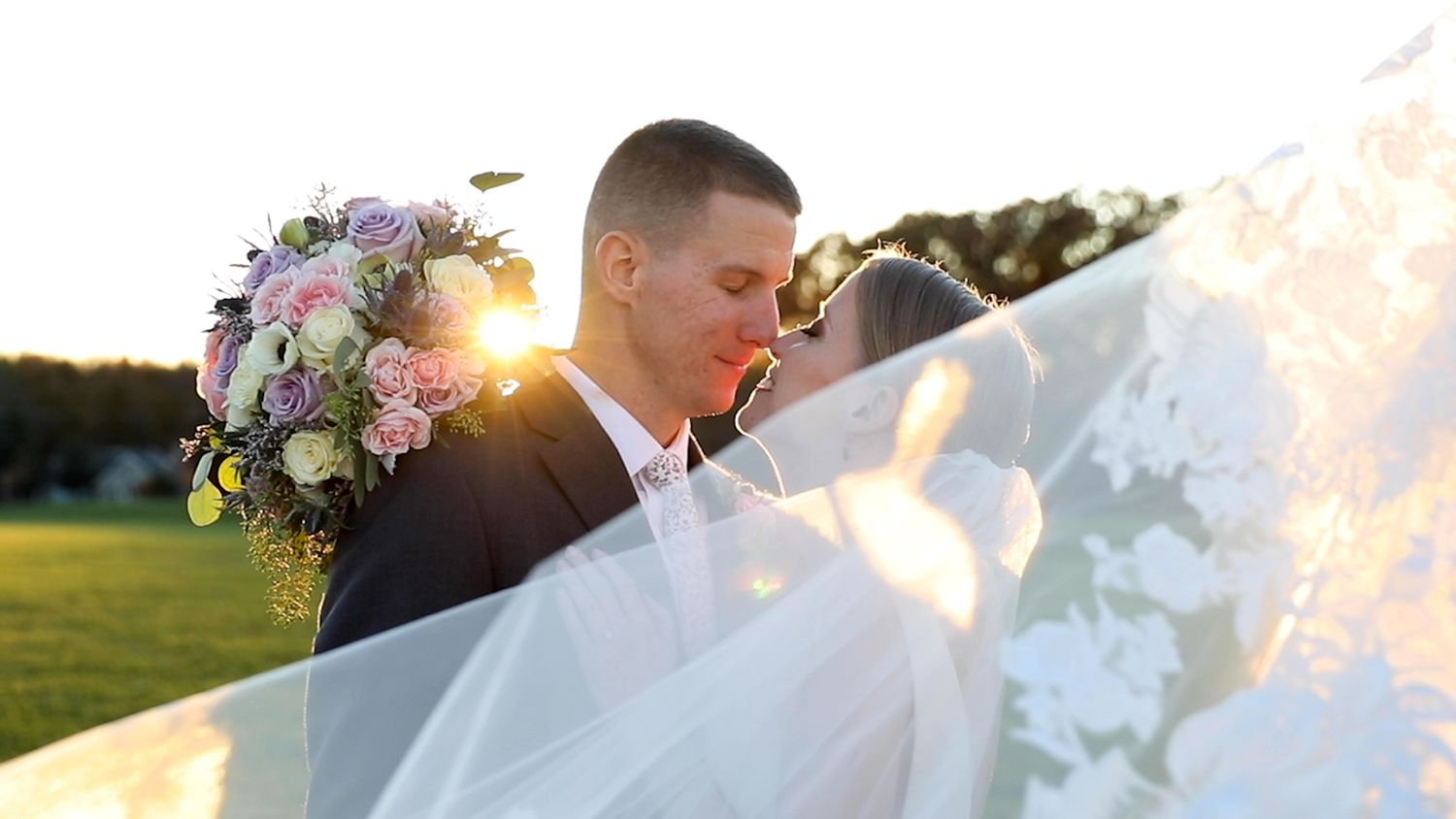 A romantic wedding portrait with sunlight streaming through a flowing veil.